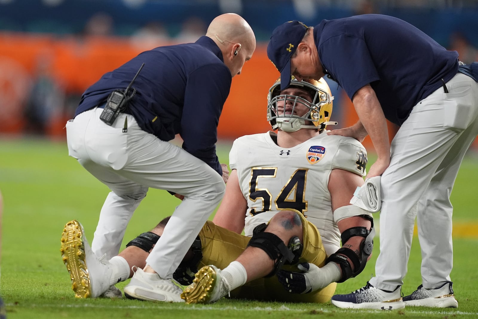 Notre Dame offensive lineman Anthonie Knapp (54) is assisted on the field during the first half of the Orange Bowl NCAA College Football Playoff semifinal game against Penn State, Thursday, Jan. 9, 2025, in Miami Gardens, Fla. (AP Photo/Rebecca Blackwell)