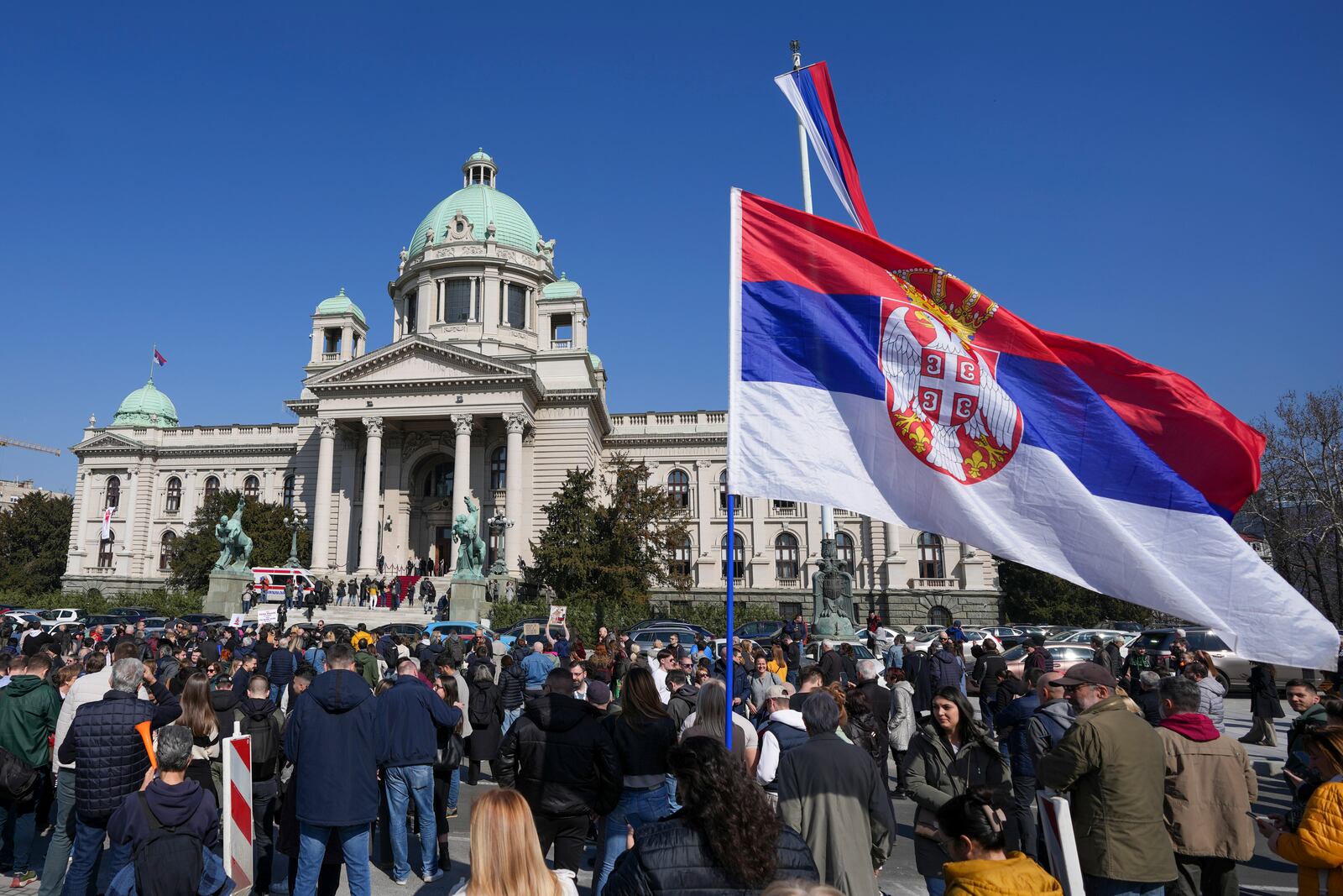 People stand in silence to commemorate the 15 victims killed after a railway concrete canopy fell in November 2024, during a Serbia's parliament session in Belgrade, Serbia, Tuesday, March 4, 2025. (AP Photo/Darko Vojinovic)