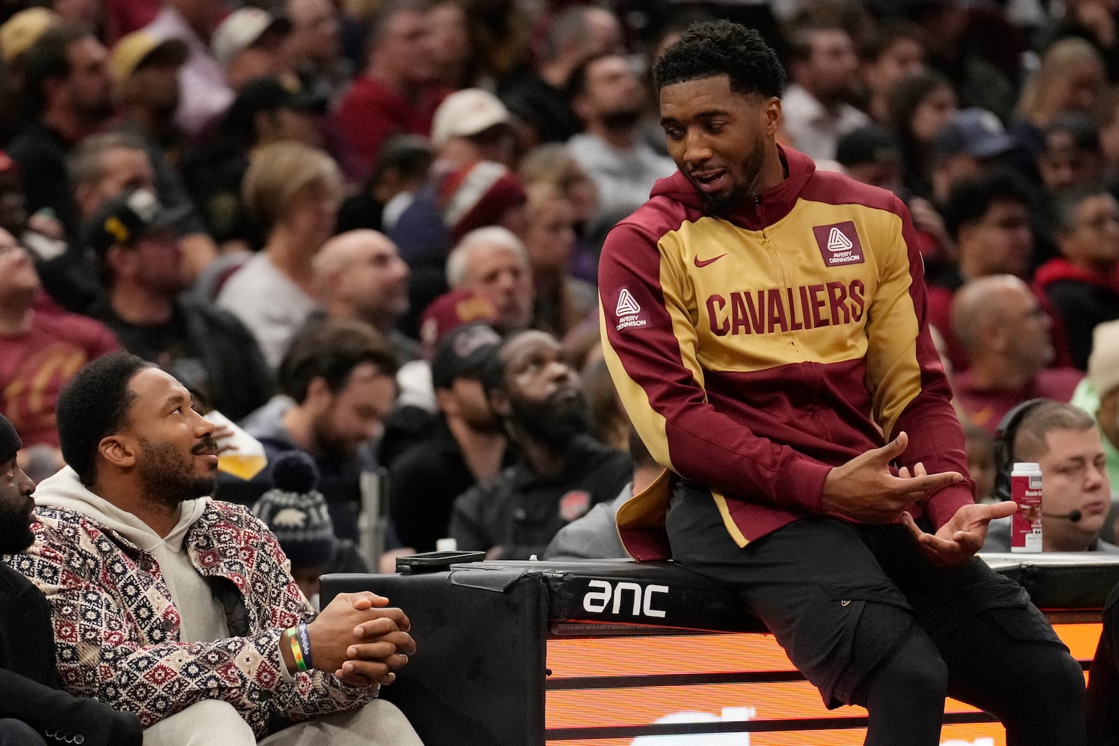 Cleveland Cavaliers guard Donovan Mitchell, right, talks with Cleveland Browns defensive end Myles Garrett, left, as he waits to return to the game in the first half of an NBA Cup basketball game against the Washington Wizards, Tuesday, Dec. 3, 2024, in Cleveland. (AP Photo/Sue Ogrocki)