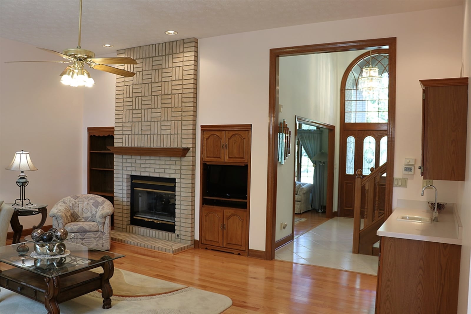 The great room, with a 10-foot ceiling, shares the other side of the living room fireplace. A wood-beam mantel matches the built-in bookcase and media nook that flank the fireplace. 