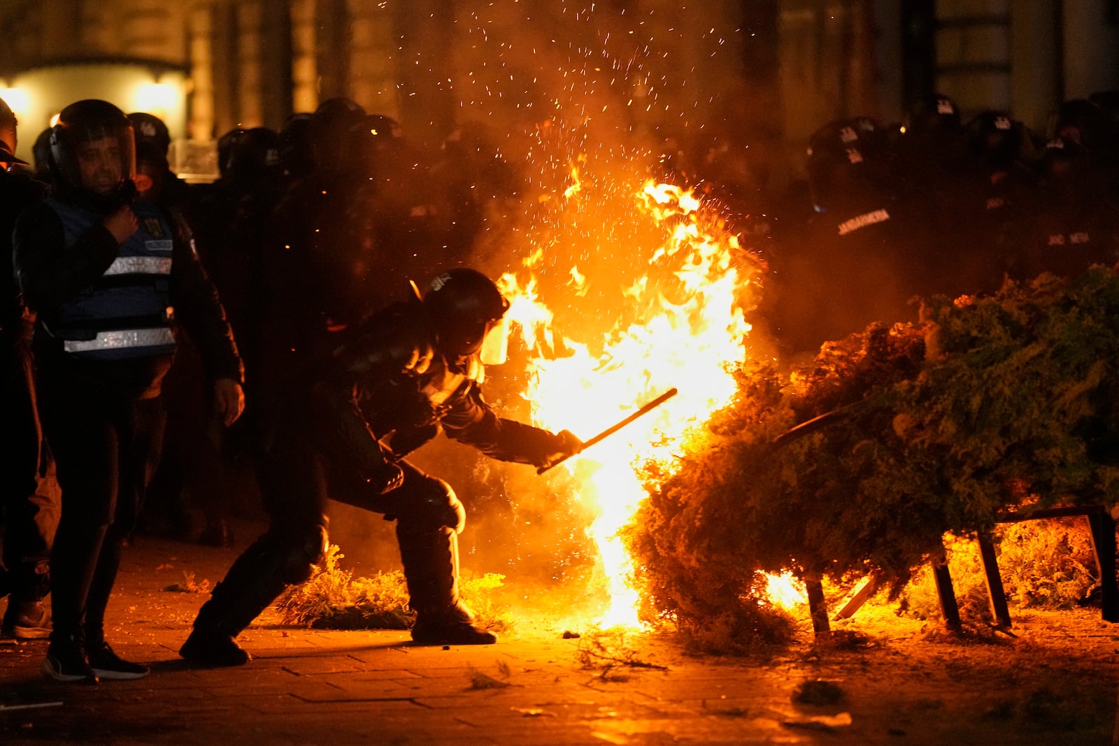 Police attempt to extinguish a fire as supporters of Calin Georgescu protested after Romania's electoral body rejected his candidacy in the presidential election rerun in Bucharest, Romania, Sunday, March 9, 2025. (AP Photo/Vadim Ghirda)