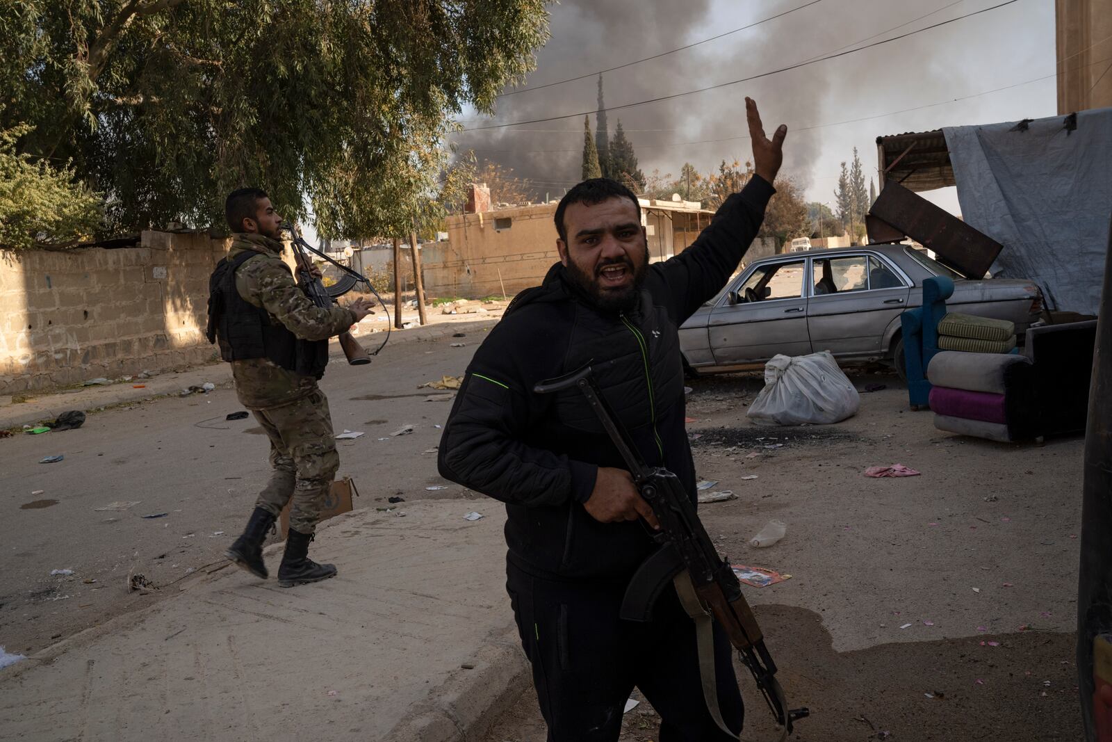 Syrian fighters take position as looters stay inside a building at a residential complex of former Bashar Assad's military officers at the village of Husseiniyeh, in the outskirts of Damascus, Syria, Sunday, Dec. 15, 2024. (AP Photo/Leo Correa)