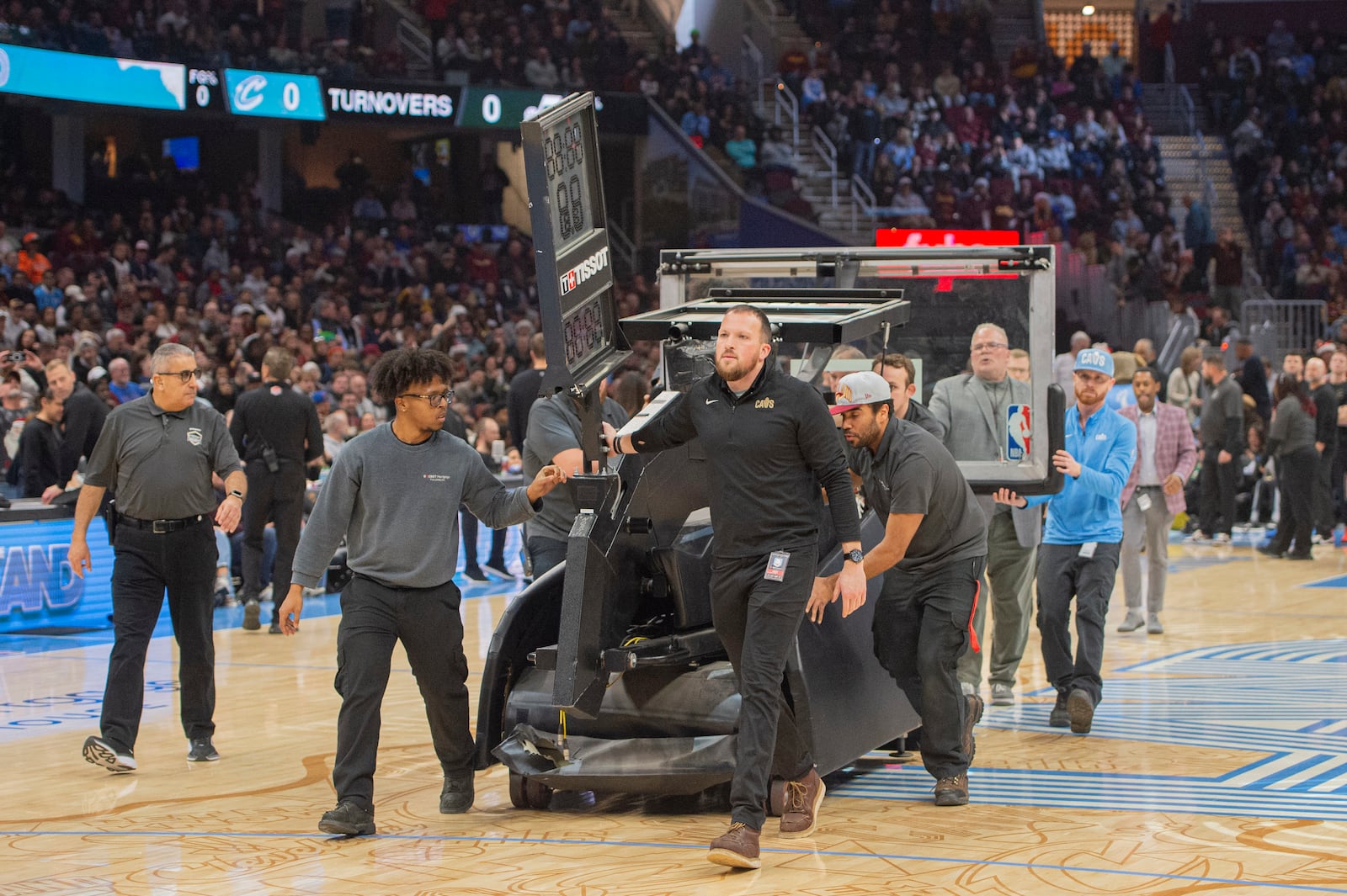 Workers bring a replacement backboard onto the court before the start of an NBA basketball game between the Cleveland Cavaliers and the Utah Jazz in Cleveland, Monday, Dec. 23, 2024. (AP Photo/Phil Long)