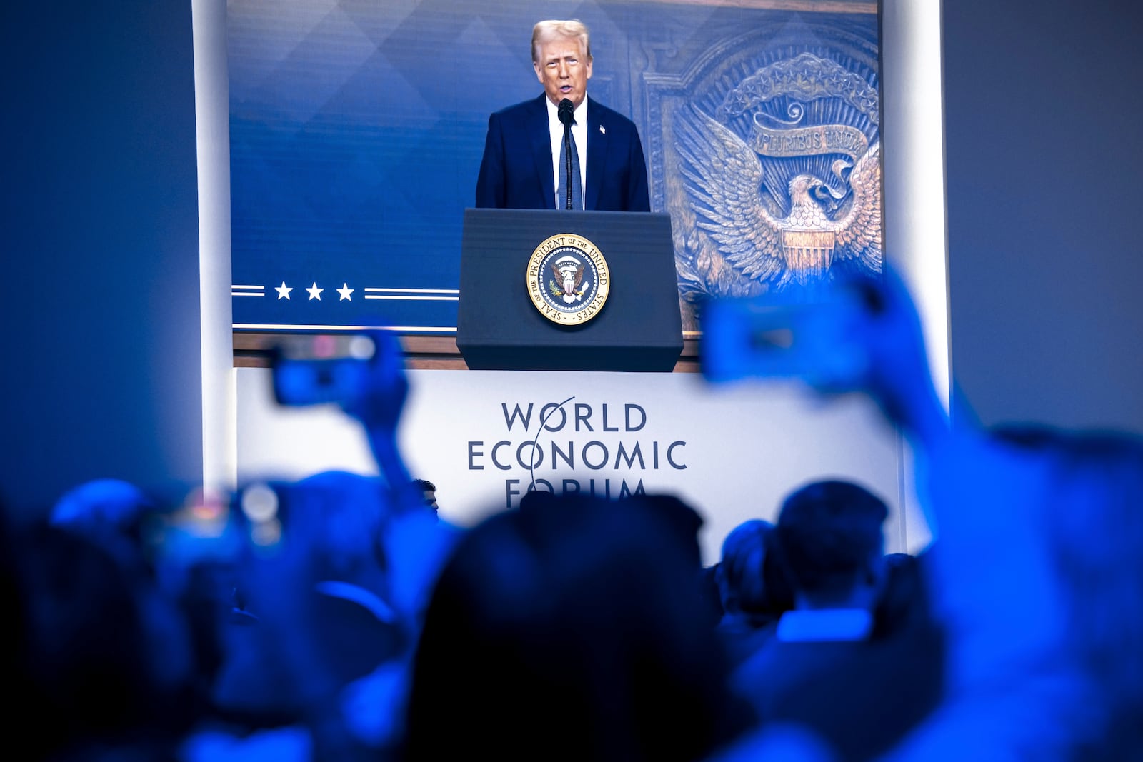 US President Donald J. Trump is shown on screens as he addresses via remote connection a plenary session in the Congress Hall, during the 55th annual meeting of the World Economic Forum (WEF), in Davos, Switzerland, Thursday, Jan. 23, 2025. (Laurent Gillieron/Keystone via AP)