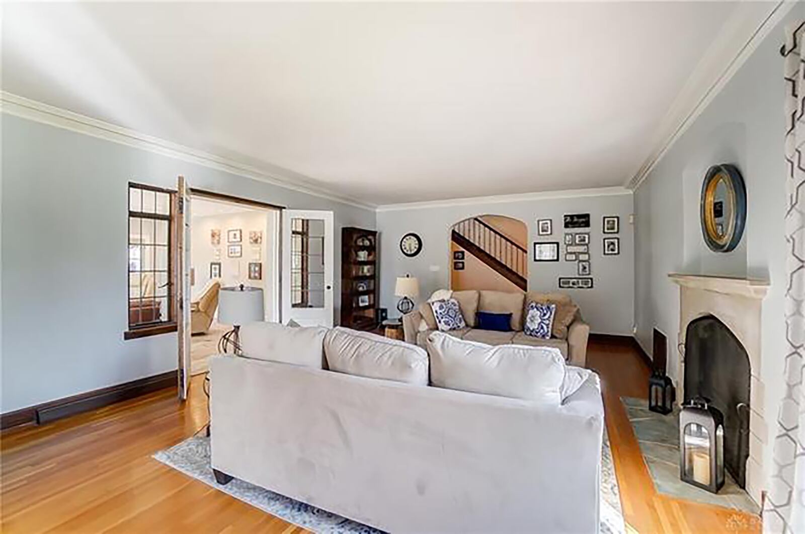 The living room has a gas fireplace, crown molding, hardwood flooring and French doors opening to the family room.