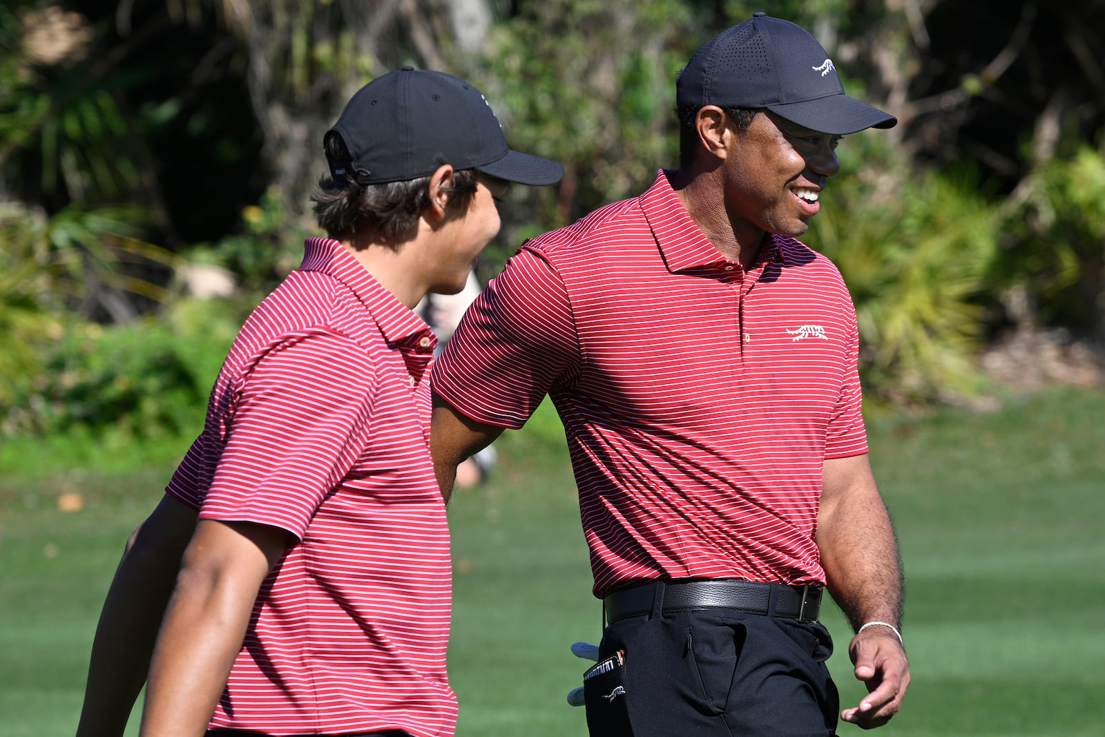 Tiger Woods, right, congratulates his son Charlie Woods after his hole-in-one on the fourth hole during the final round of the PNC Championship golf tournament, Sunday, Dec. 22, 2024, in Orlando, Fla. (AP Photo/Phelan M. Ebenhack)