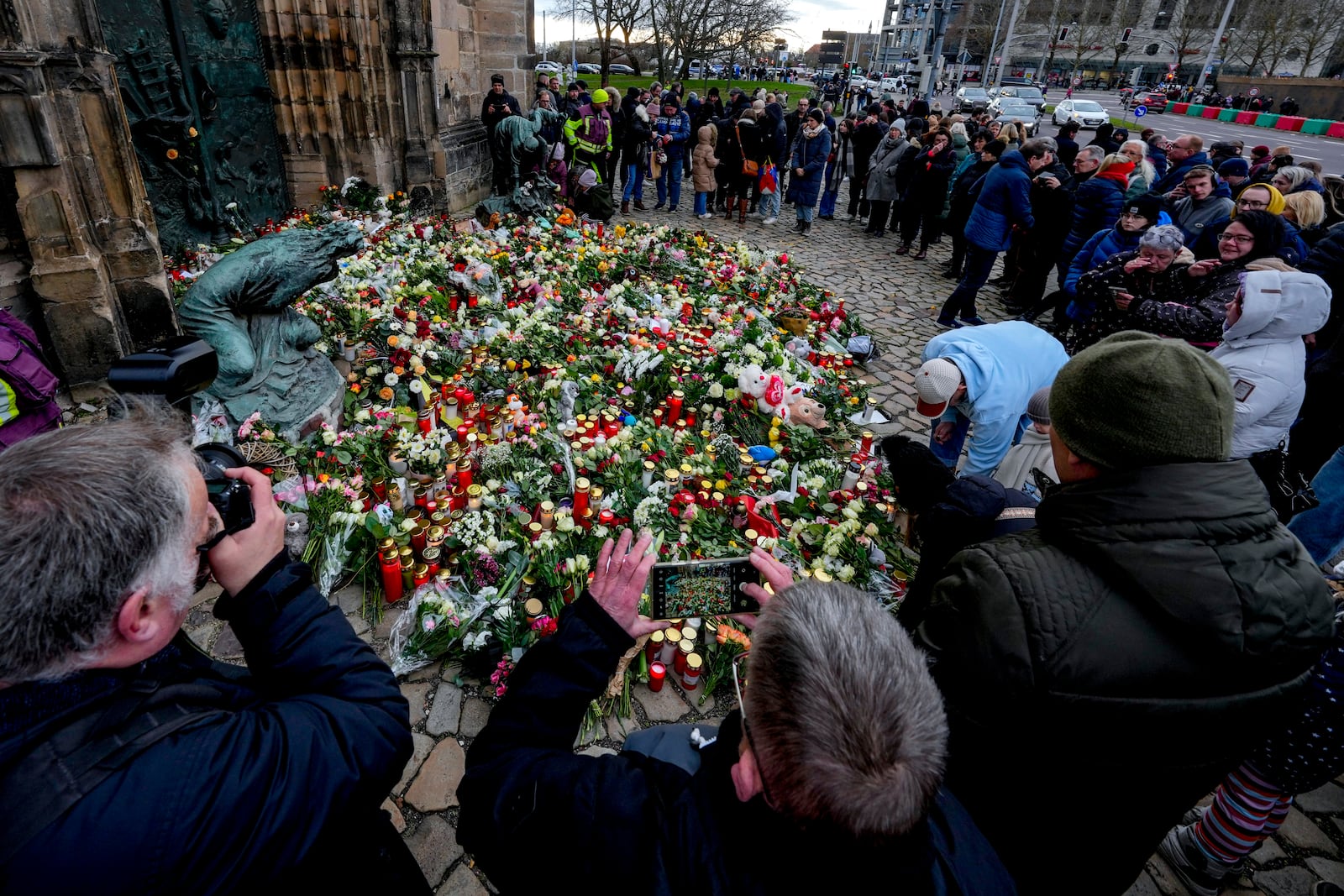 People lay flowers at the entrance of a church near a Christmas Market, where a car drove into a crowd on Friday evening, in Magdeburg, Germany, Saturday, Dec. 21, 2024. (AP Photo/Michael Probst)