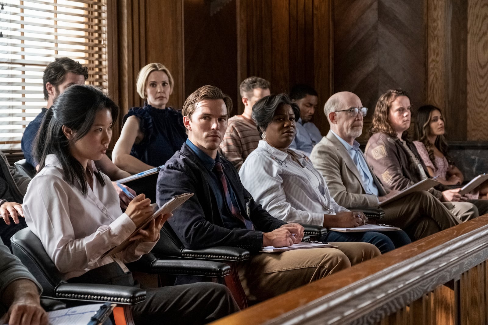 This image released by Warner Bros. Entertainment shows Leslie Bibb, top center, Chikako Fukuyama, from bottom left, Nicholas Hoult, Adrienne C. Moore, J.K. Simmons, Drew Scheid, and Hedy Nasser in a scene from "Juror #2". (Warner Bros. Entertainment via AP)