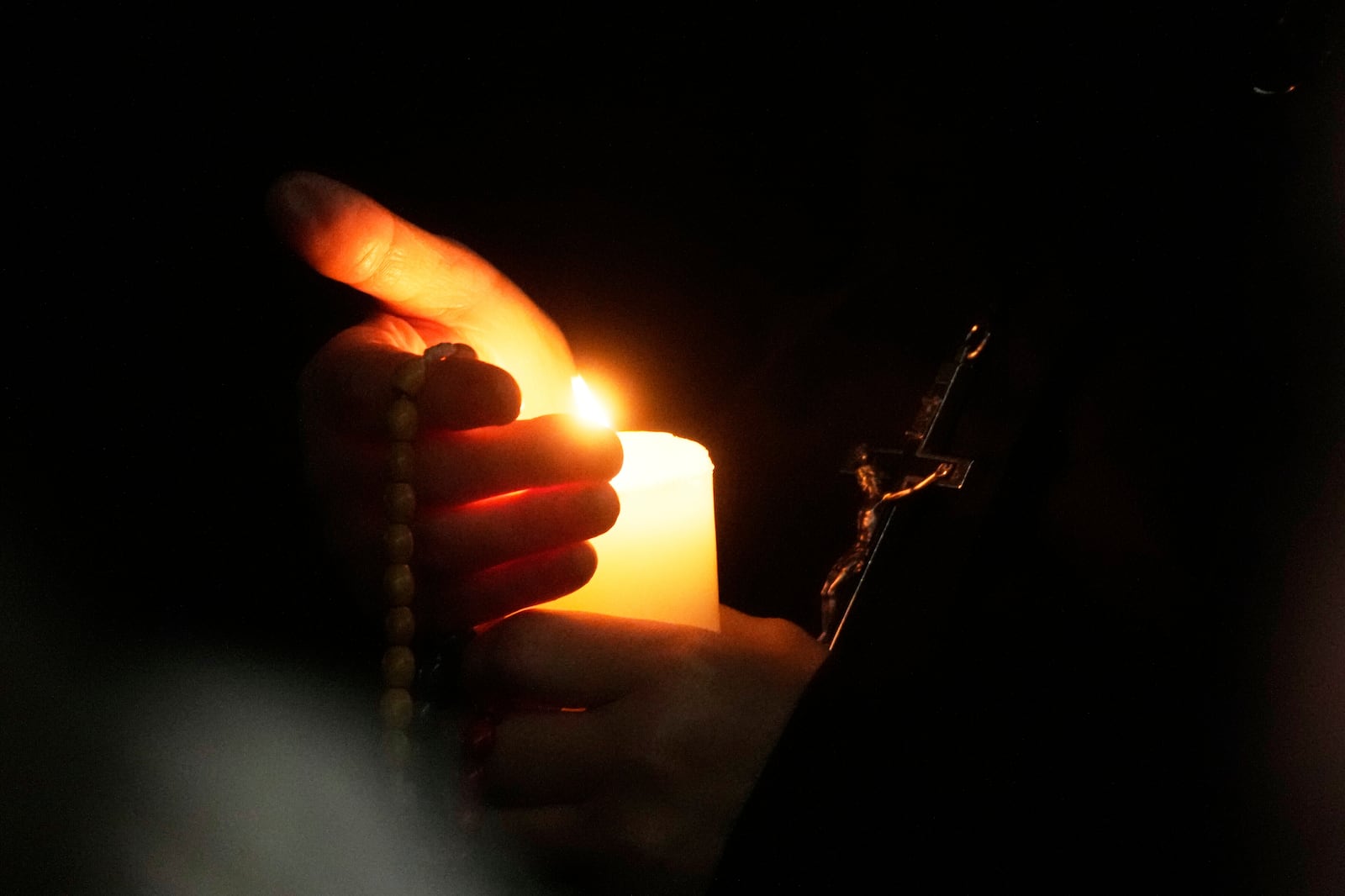 A nun holds a candle as she prays in St. Peter's Square, at the Vatican, during a vigil rosary for the recovery of Pope Francis, Tuesday, March 18, 2025. (AP Photo/Gregorio Borgia)