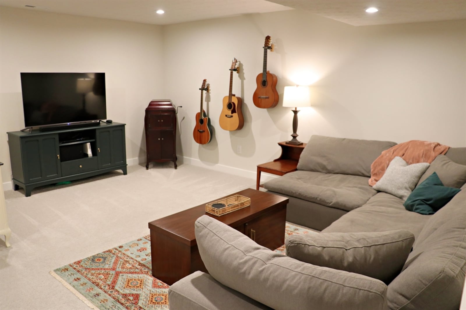 A spacious family room with a media area and ceiling lights is in the basement. 