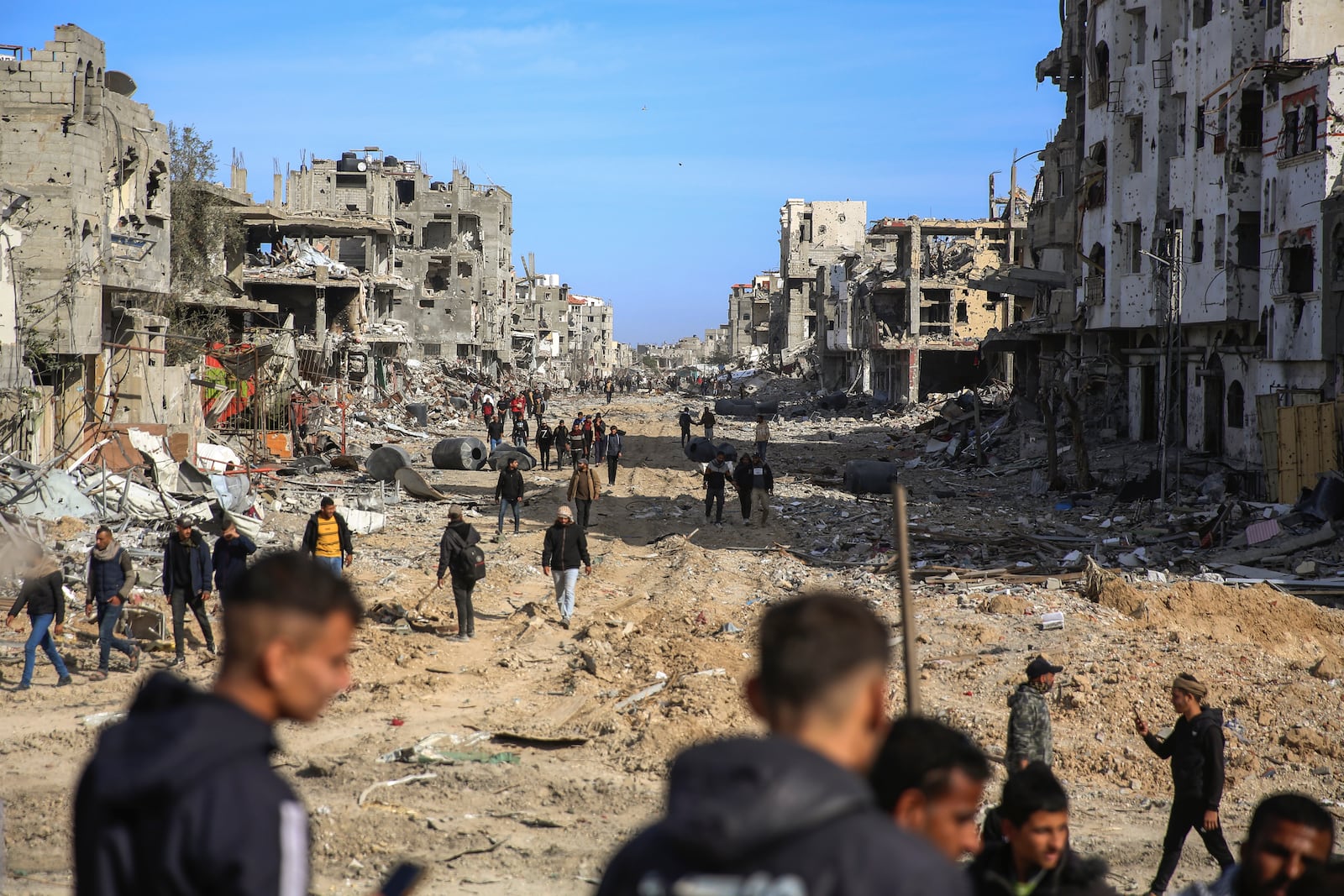 Palestinians walk amongst the destruction caused by the Israeli air and ground offensive, Sunday, Jan. 19, 2025, in Rafah, as a ceasefire deal between Israel and Hamas went into effect. (AP Photo/Mohammad Hajjar)