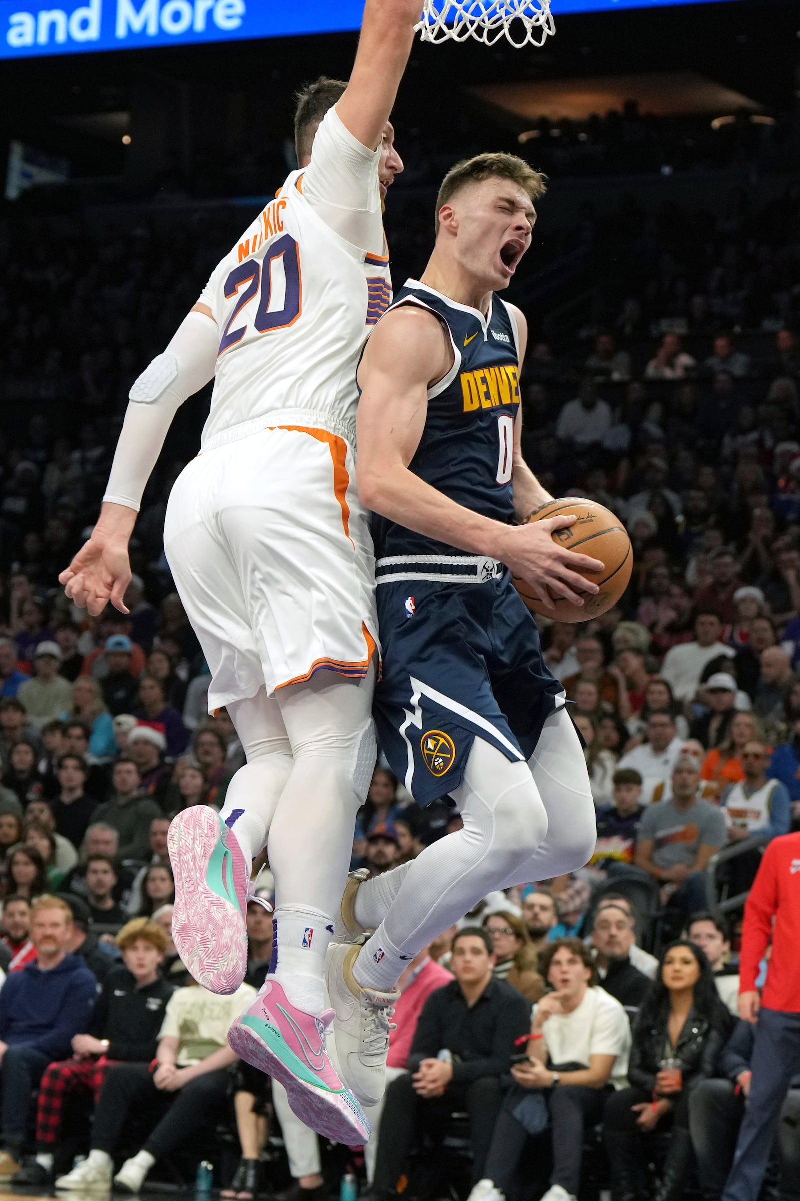 Denver Nuggets guard Christian Braun gets fouled by Phoenix Suns center Jusuf Nurkic (20) during the first half of an NBA basketball game, Wednesday, Dec. 25, 2024, in Phoenix. (AP Photo/Rick Scuteri)