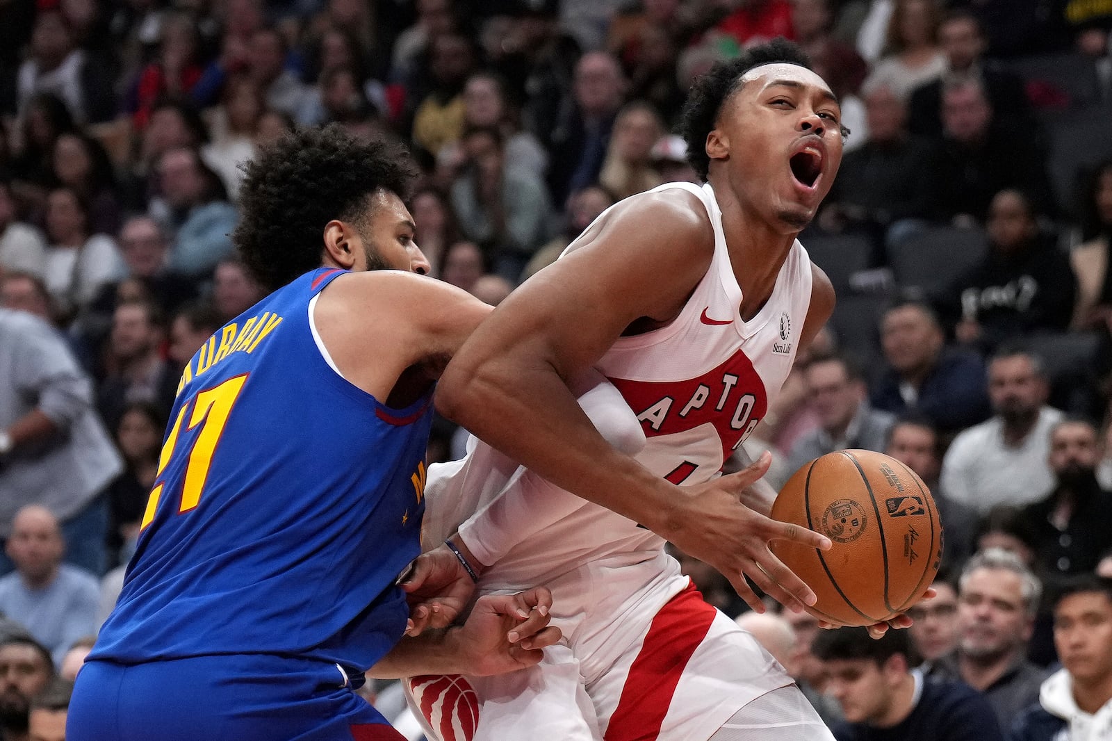 Toronto Raptors forward Scottie Barnes, right, reacts as he drives into Denver Nuggets guard Jamal Murray, left, during first-half NBA basketball game action in Toronto, Monday, Oct. 28, 2024. (Nathan Denette/The Canadian Press via AP)