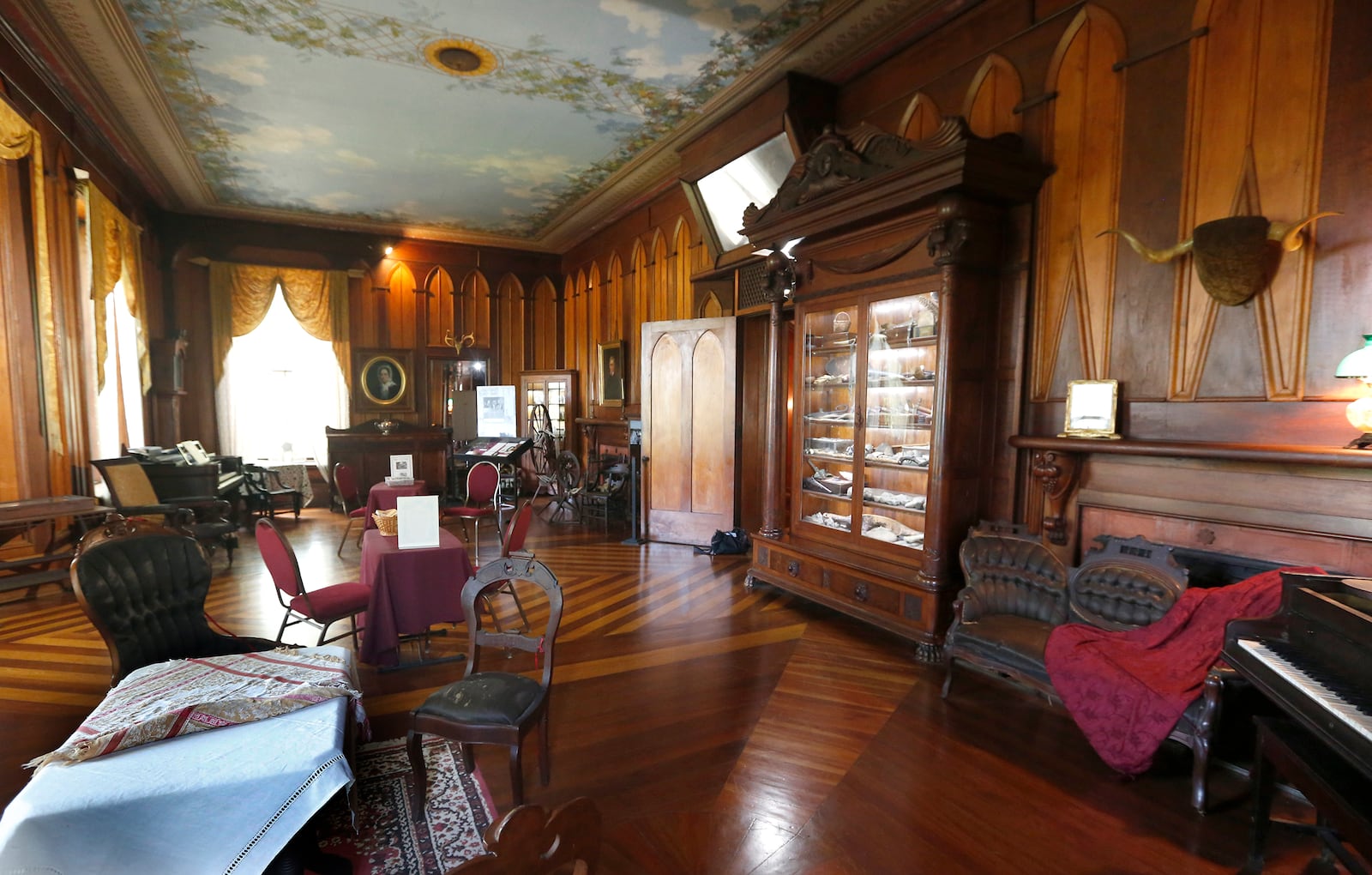 Margaret Piatt calls the drawing room at Mac-A-Cheek "the best room with the best things in it,"  It was the original portion of the home that opened as a museum in 1912. A massive cabinet filled with natural history treasures collected by William McCoy Piatt is at right. LISA POWELL / STAFF