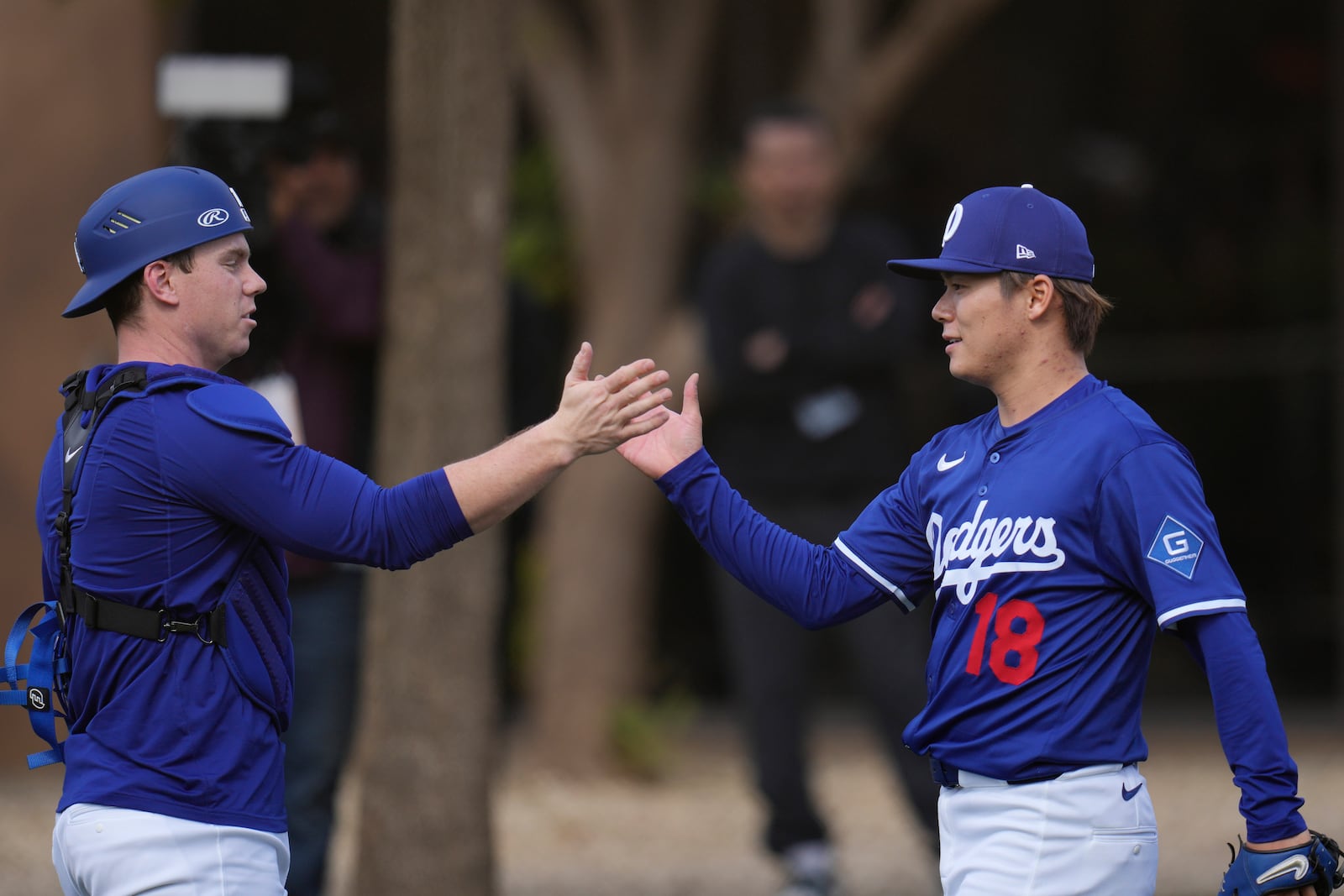 Los Angeles Dodgers pitcher Yoshinobu Yamamoto (18), of Japan, slaps hands with Dodgers catcher Will Smith after a pitching session at the Dodgers baseball spring training facility Tuesday, Feb. 11, 2025, in Phoenix. (AP Photo/Ross D. Franklin)