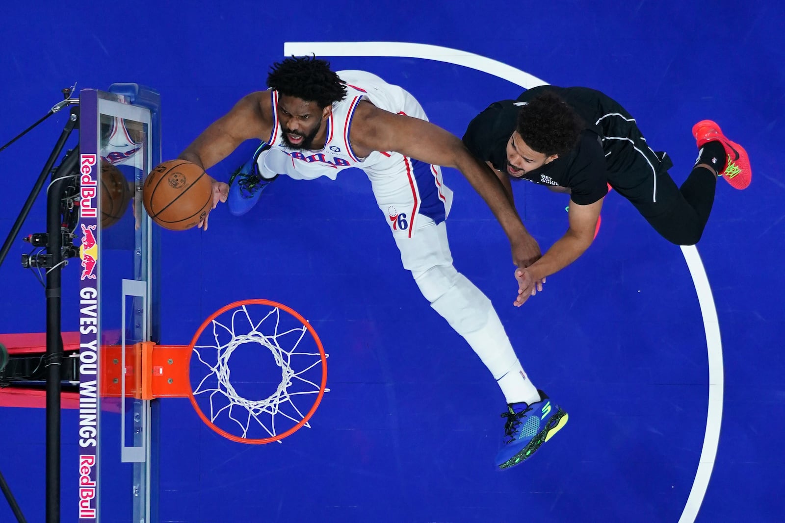 Philadelphia 76ers' Joel Embiid, left, goes up for a shot past Brooklyn Nets' Cameron Johnson during the first half of an NBA basketball game, Saturday, Feb. 22, 2025, in Philadelphia. (AP Photo/Matt Slocum)