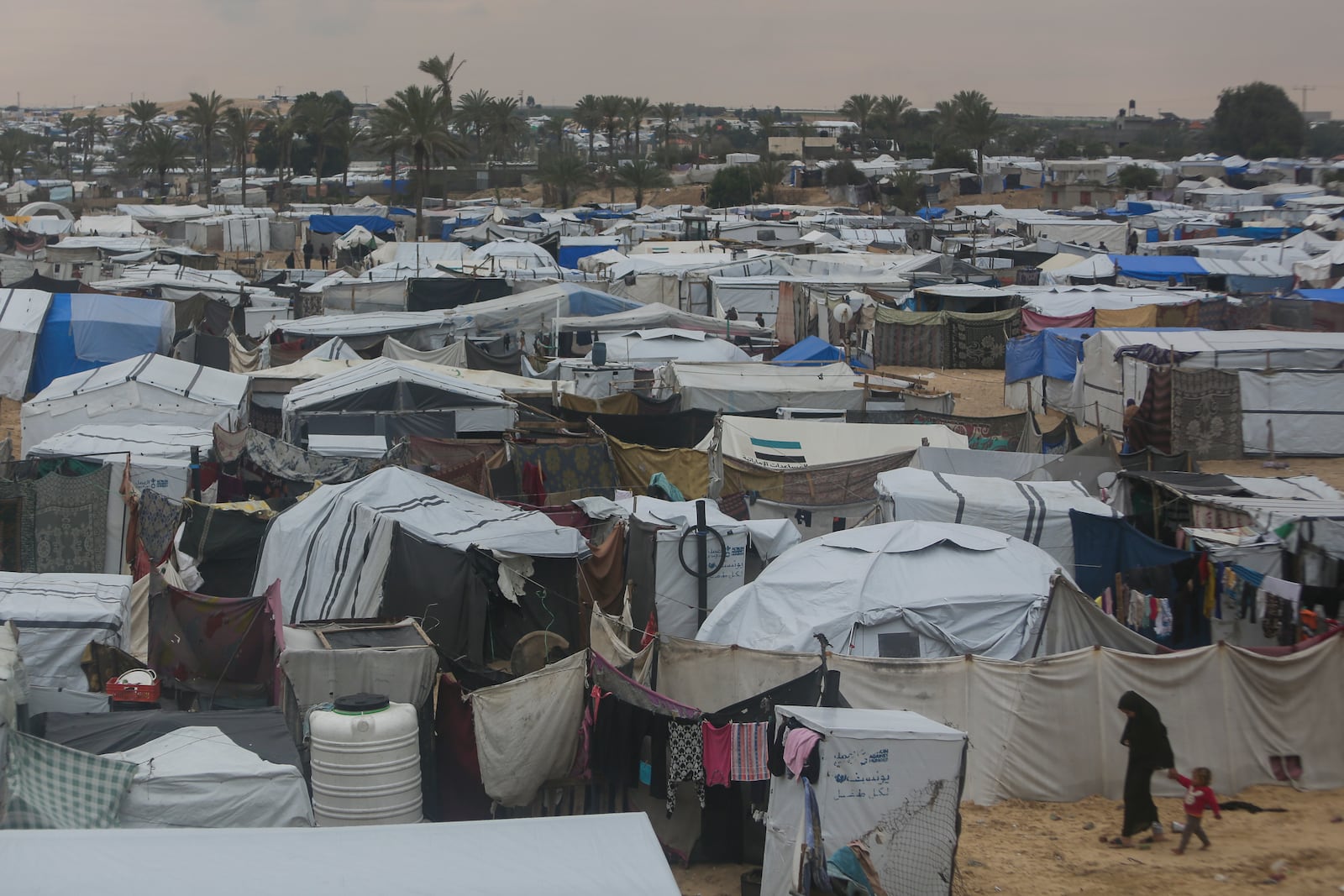 Palestinians displaced by the Israeli air and ground offensive on the Gaza Strip walk through a makeshift tent camp in Muwasi, Rafah, southern Gaza, Monday, Feb. 24, 2025. (AP Photo/Jehad Alshrafi)