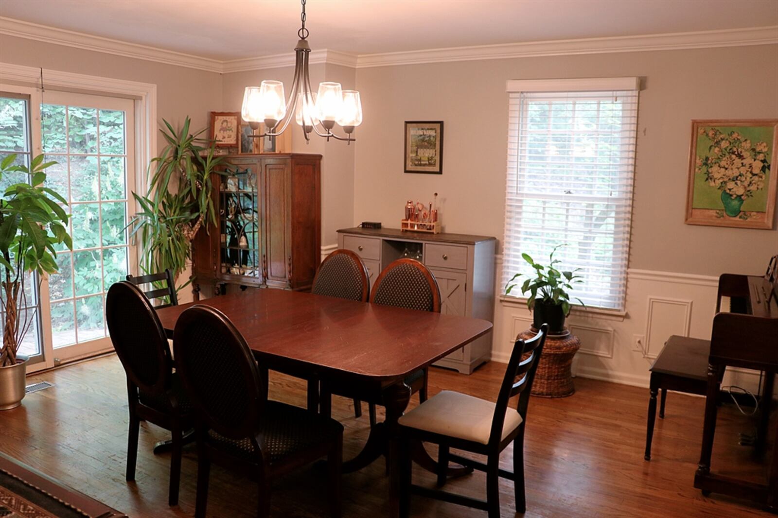 The dining room has crown molding and wainscoting. Sliding patio doors open out to the backyard paver-brick patio that curves to a second set of patio doors.