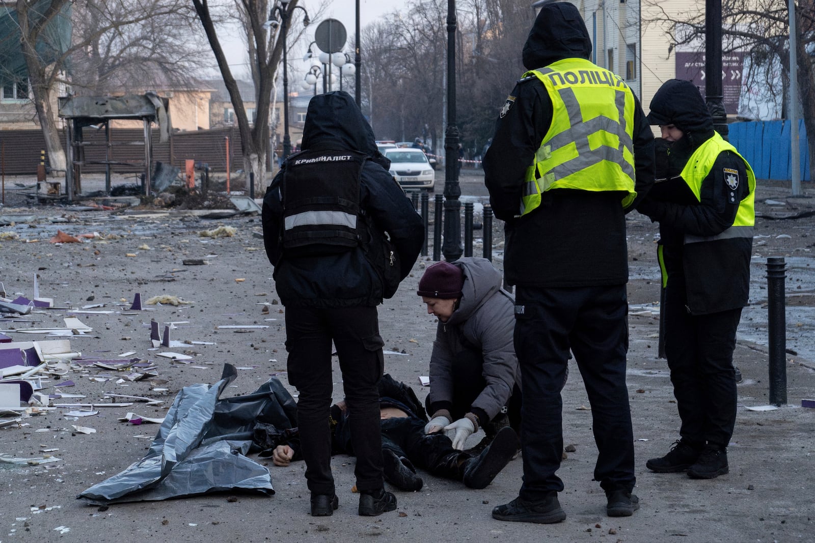 Police workers observe the body of a man which was killed after a Russian attack, which also injured multiple people in Kyiv, Ukraine, Wednesday, Feb. 12, 2025. (AP Photo/Alex Babenko)