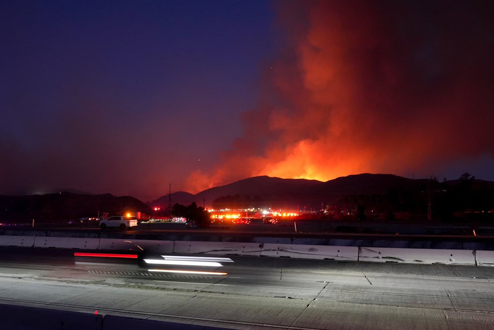 Traffic makes its way along Interstate 5 as the Hughes Fire burns in the background Wednesday, Jan. 22, 2025, in Castaic, Calif. (AP Photo/Marcio Jose Sanchez)