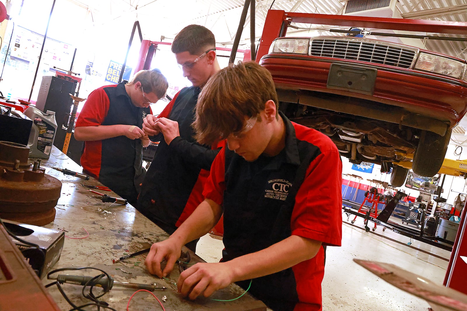 CTC students in the Automotive Technology & Motorcycle Maintenance program, Korey Kolowena, senior, Tecumseh High School, Greg Lange, senior, Shawnee High School and Caleb Weese, senior, Greenon High School, work on their soldering skills Friday, Oct. 18, 2024. BILL LACKEY/STAFF