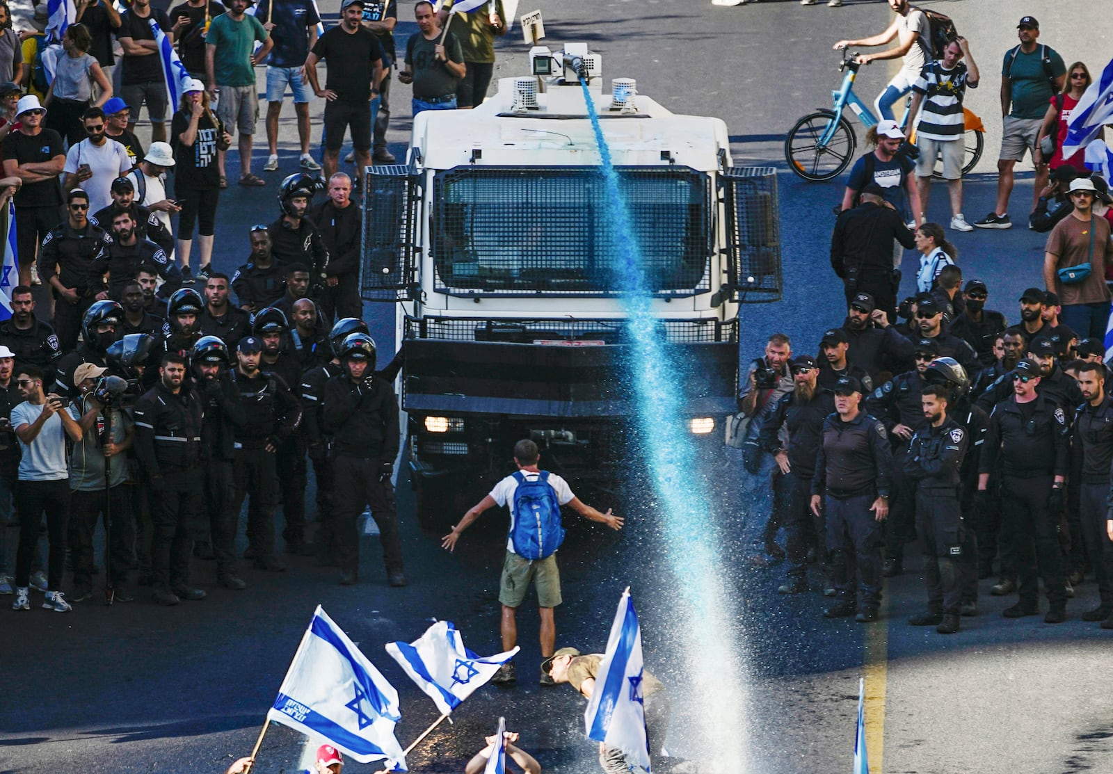 FILE - A person stands in front of an Israeli police water cannon being used to disperse demonstrators blocking a road during a protest against plans by Prime Minister Benjamin Netanyahu's government to overhaul the judicial system, in Jerusalem, July 24, 2023. (AP Photo/Ariel Schalit, File)