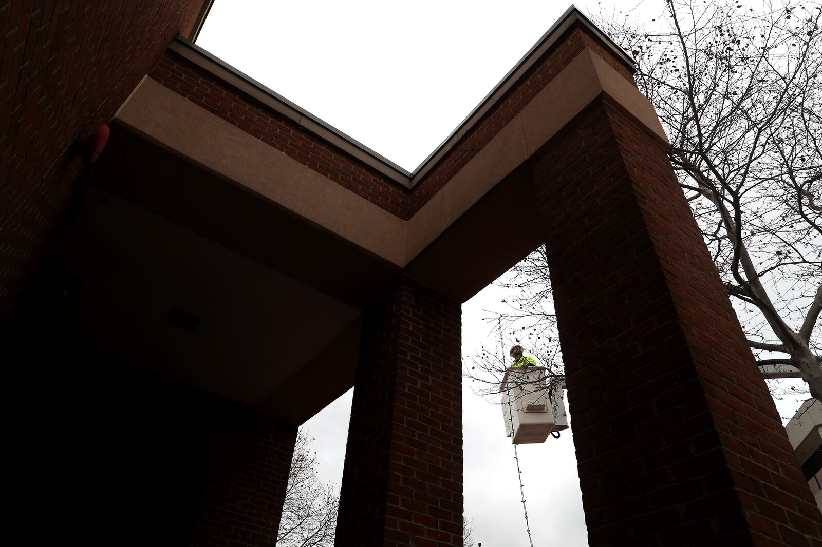 A worker from the City of Springfield Service Department uses a lift as he takes down the last of the holiday lights along High Street outside the Courtyard by Marriott Tuesday. BILL LACKEY/STAFF