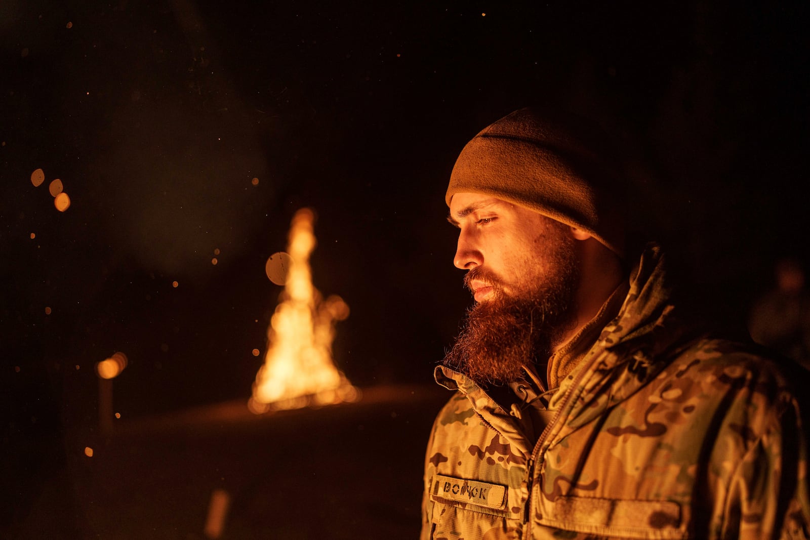 A Ukrainian serviceman aka Vovchok of 3rd assault brigade throws gunpowder into a fire during memorial ceremony of his fallen comrades during the winter solstice in Kharkiv region, Ukraine, Dec. 22, 2024. (AP Photo/Evgeniy Maloletka)