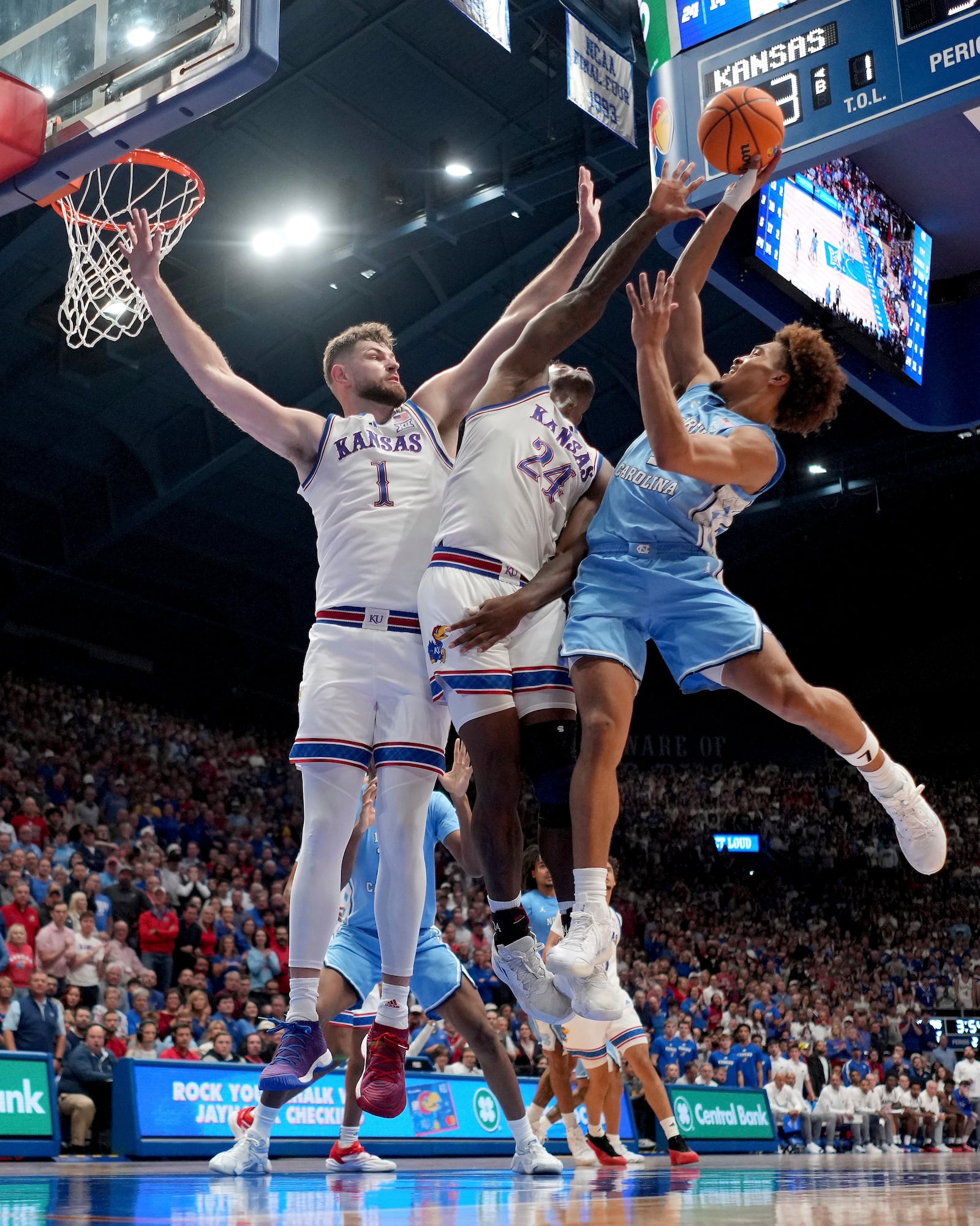 North Carolina guard Seth Trimble, left, shoots under pressure from Kansas center Hunter Dickinson (1) and forward KJ Adams Jr. (24) during the second half of an NCAA college basketball game Friday, Nov. 8, 2024, in Lawrence, Kan. Kansas won 92-89. (AP Photo/Charlie Riedel)