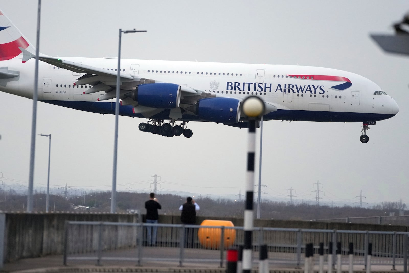 People watch a British Airways plane landing as authorities announced a partial resumption of flights after a fire at a nearby electrical substation has caused a closure of Europe's busiest airport in London, Friday, March 21, 2025.(AP Photo/Kin Cheung)