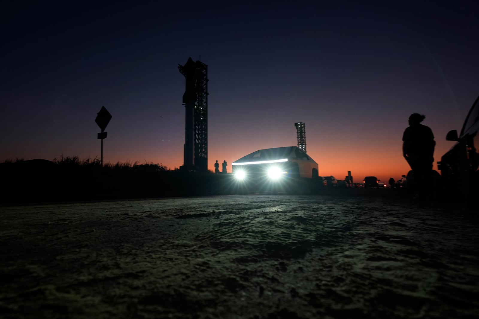 FILE - A Tesla Cybertruck passes as the sun sets behind SpaceX's mega rocket Starship, Oct. 12, 2024, in Boca Chica, Texas. (AP Photo/Eric Gay, File)