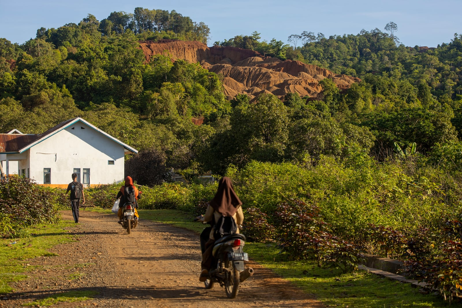 Students head to school as a hill that has been mined for nickel ore is visible in the background on Kabaena Island in South Sulawesi, Indonesia, Saturday, Nov. 16, 2024,. (AP Photo/Yusuf Wahil)