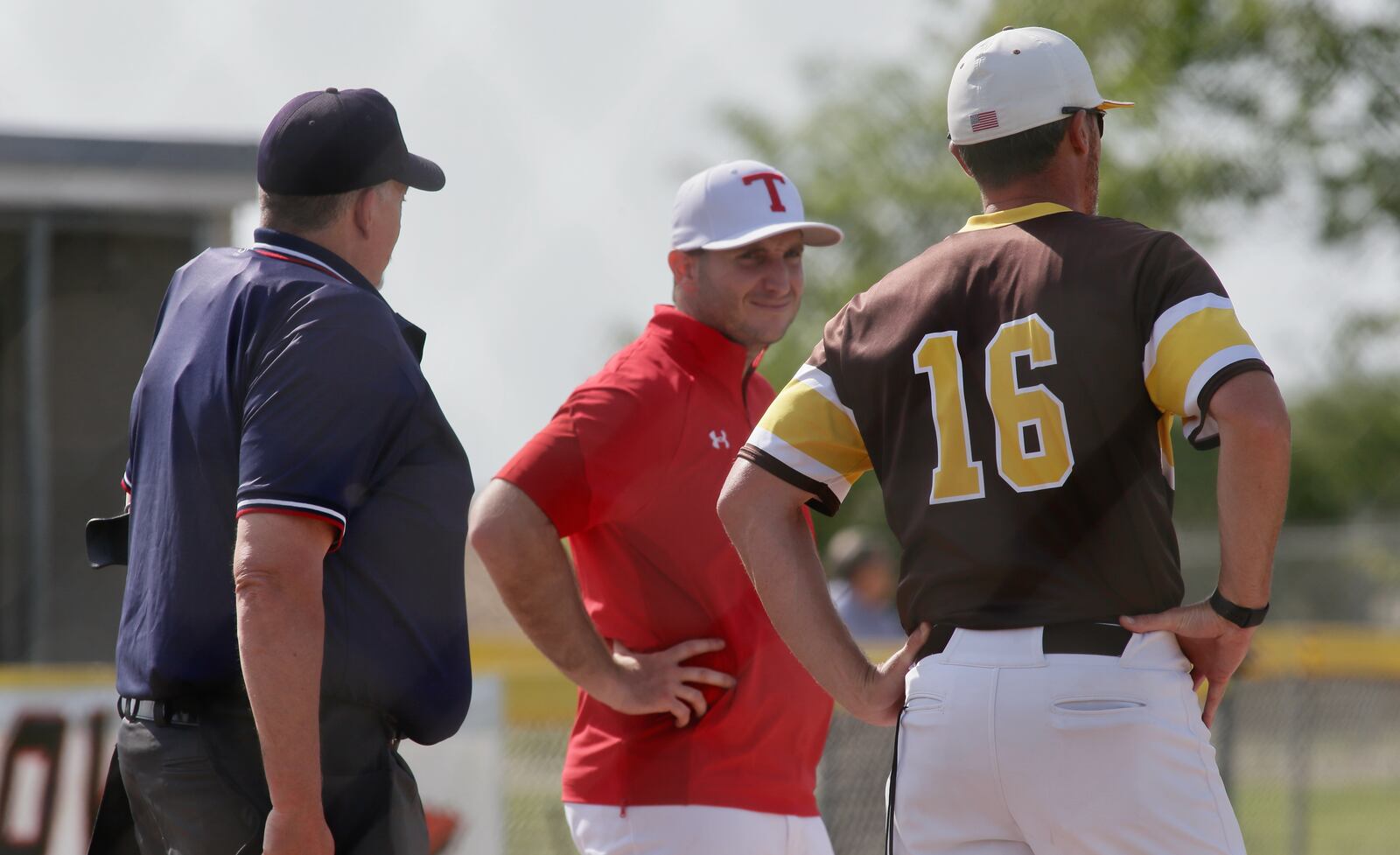 Tippecanoe's Bryan Gorski talks with the umpires and Kenton Ridge's Aaron Shaffer before a a Division II district semifinal on Tuesday, May 24, 2022, at Tecumseh High School in New Carlisle. David Jablonski/Staff