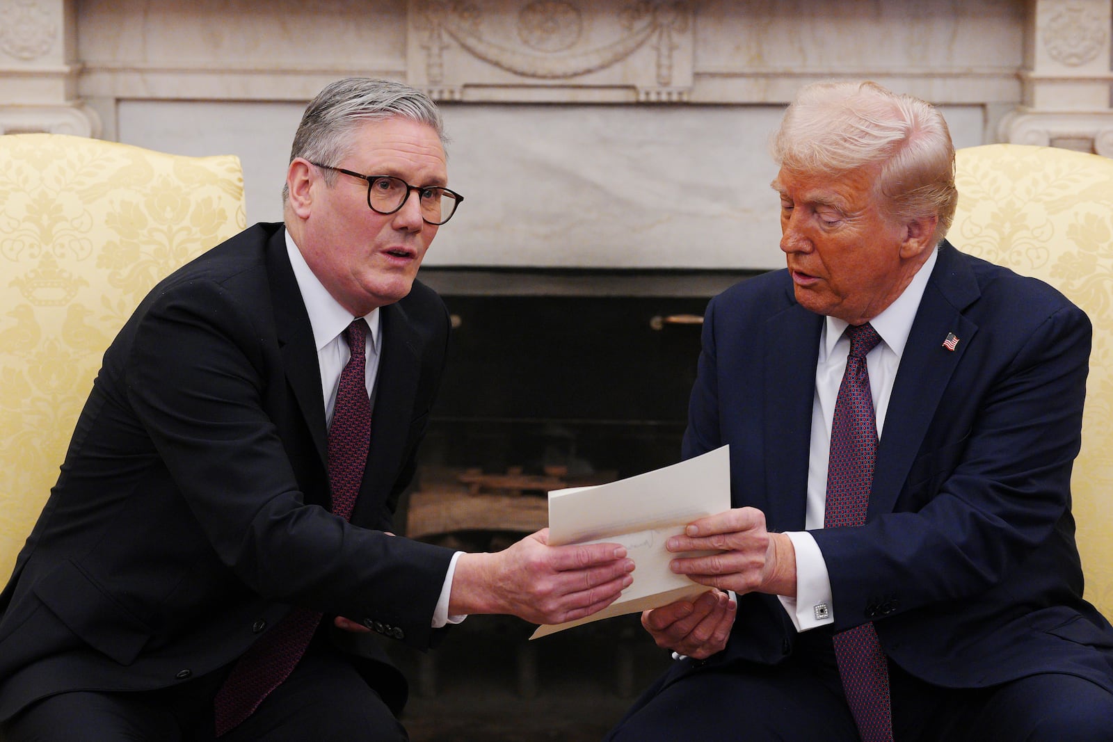 British Prime Minister Keir Starmer, left, hands an invitation from King Charles III to President Donald Trump at the White House, Thursday, Feb. 27, 2025, in Washington. (Carl Court/Pool via AP)