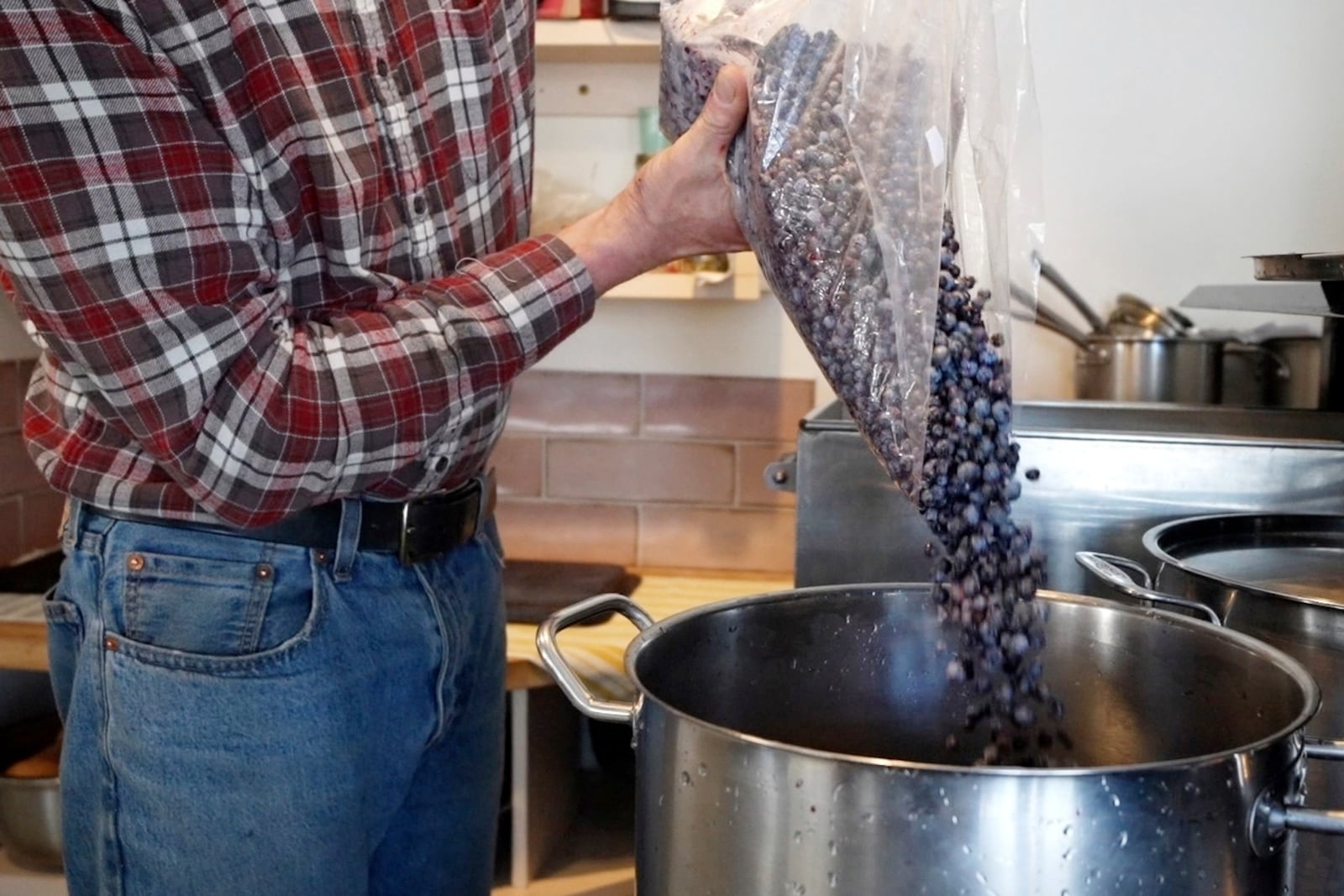 Hugh Lassen pours wild blueberries into a pot during the making of blueberry spread, Monday, Feb. 10, 2025, in Cherryfield, Maine. (AP Photo/Robert F. Bukaty)