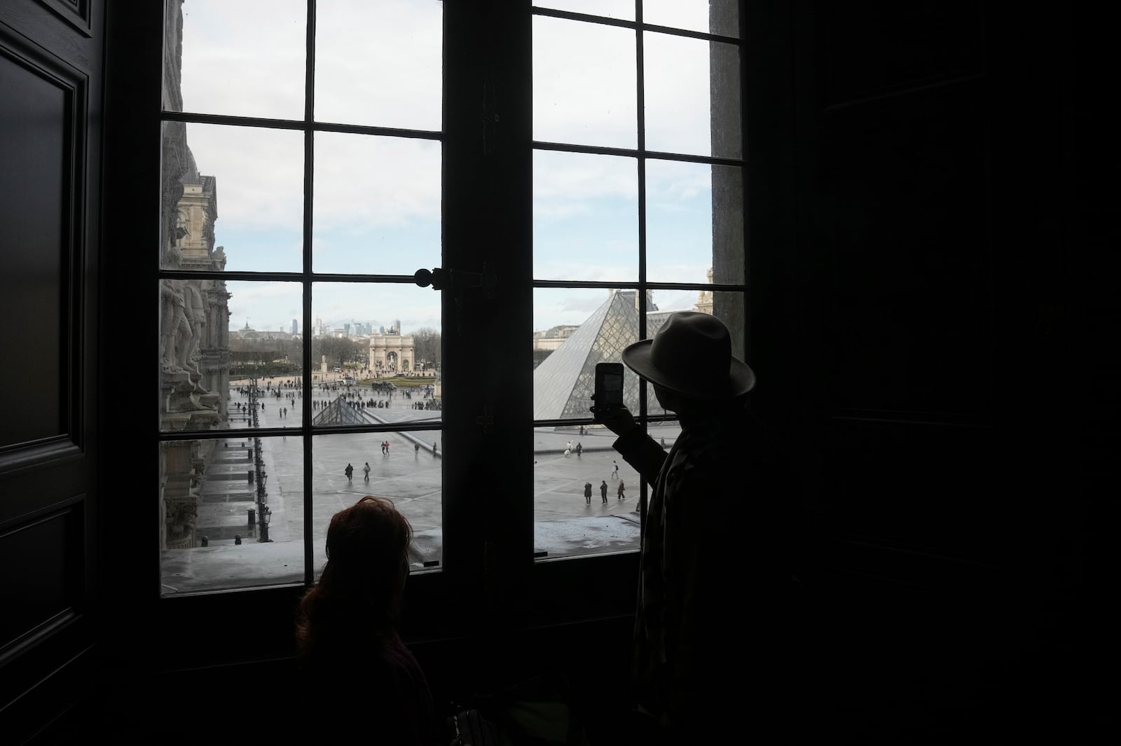 A visitor uses his mobile phone to photograph the courtyard of the Louvre museum, Monday, Jan. 27, 2025 in Paris. (AP Photo/Thibault Camus)