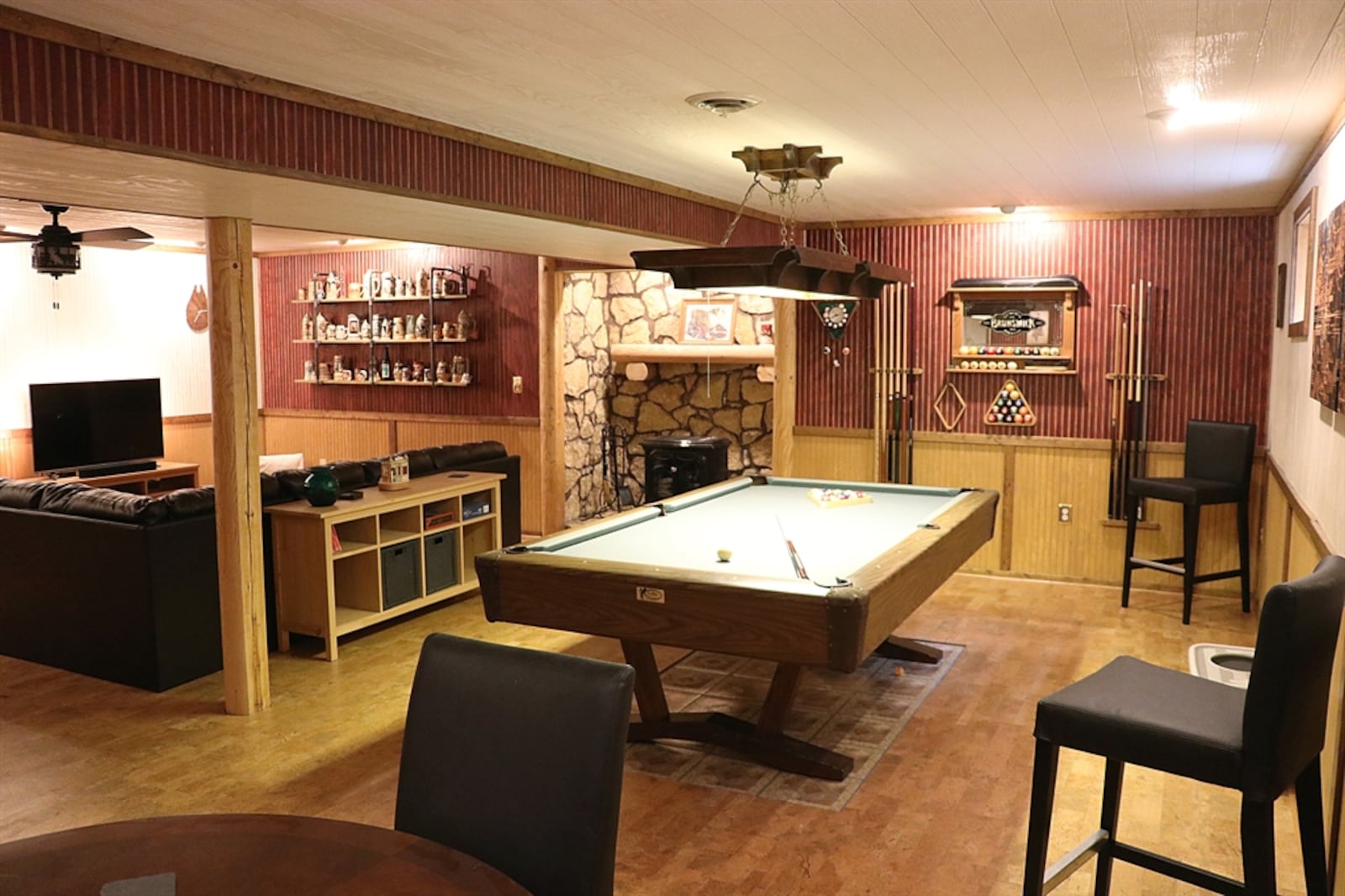 Various shades of shiplap and bead board complement the log support beams that divide the basement into a family room and recreation area.