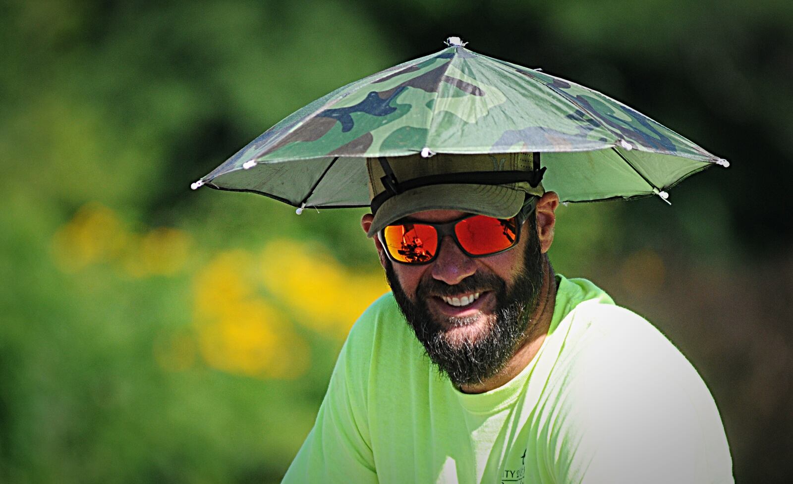 City of Kettering employee Joe Staten works to beat the heat with his umbrella hat at Delco Park on Wednesday, June 26, 2019.