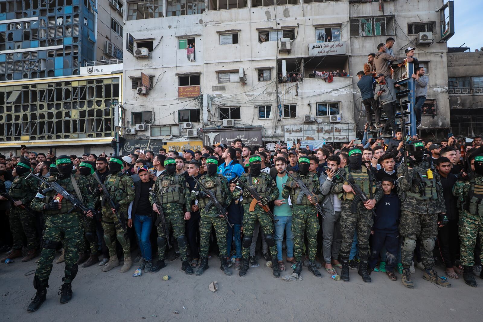 Fighters from the Qassam Brigades, the military wing of Hamas, control the crowd as Red Cross vehicles manoeuvre to collect Israeli hostages to be released under a ceasefire agreement between Israel and Hamas, in Gaza City, Sunday, Jan. 19, 2025. (AP Photo/Abed Hajjar)