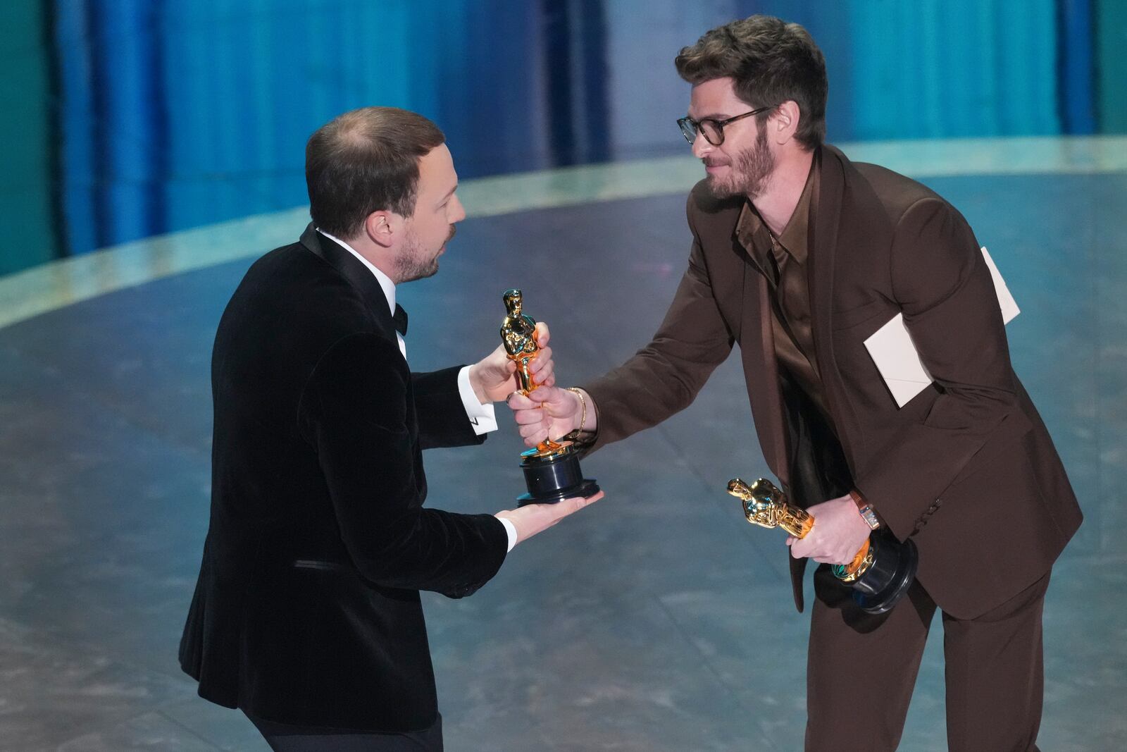 Gints Zilbalodis, left, accepts the award for best animated feature film for "Flow" from Andrew Garfield during the Oscars on Sunday, March 2, 2025, at the Dolby Theatre in Los Angeles. (AP Photo/Chris Pizzello)