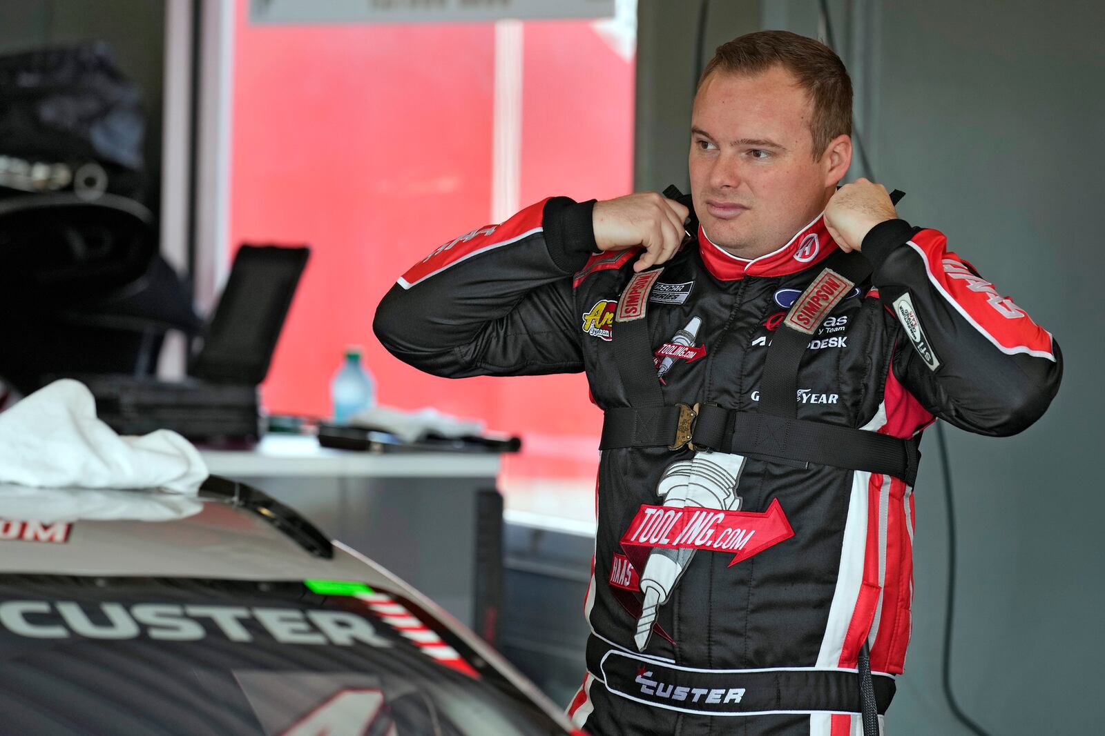 Cole Custer puts on his head and neck device before a practice for the NASCAR Daytona 500 auto race Wednesday, Feb. 12, 2025, at Daytona International Speedway in Daytona Beach, Fla. (AP Photo/Chris O'Meara)