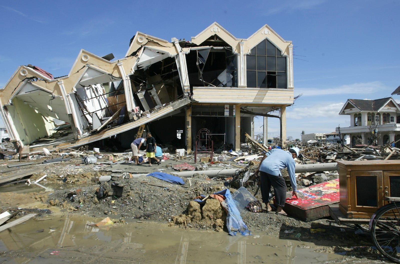 A survivor rummages through the debris at the commercial area of Banda Aceh, the capital of Aceh province in northwest Indonesia, Dec. 31, 2004.(AP Photo/Bullit Marquez, File)