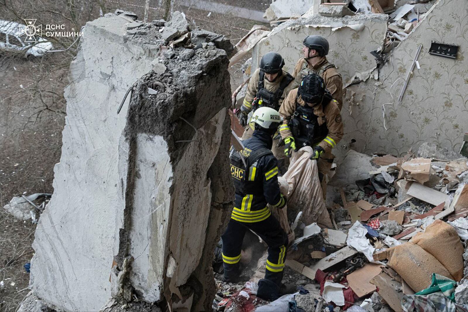 In this photo provided by the Ukrainian Emergency Service, rescuers search for civilians who were killed when a Russian drone hit an apartment building in Sumy, Ukraine, Thursday, Jan. 30, 2025. (Ukrainian Emergency Service via AP)