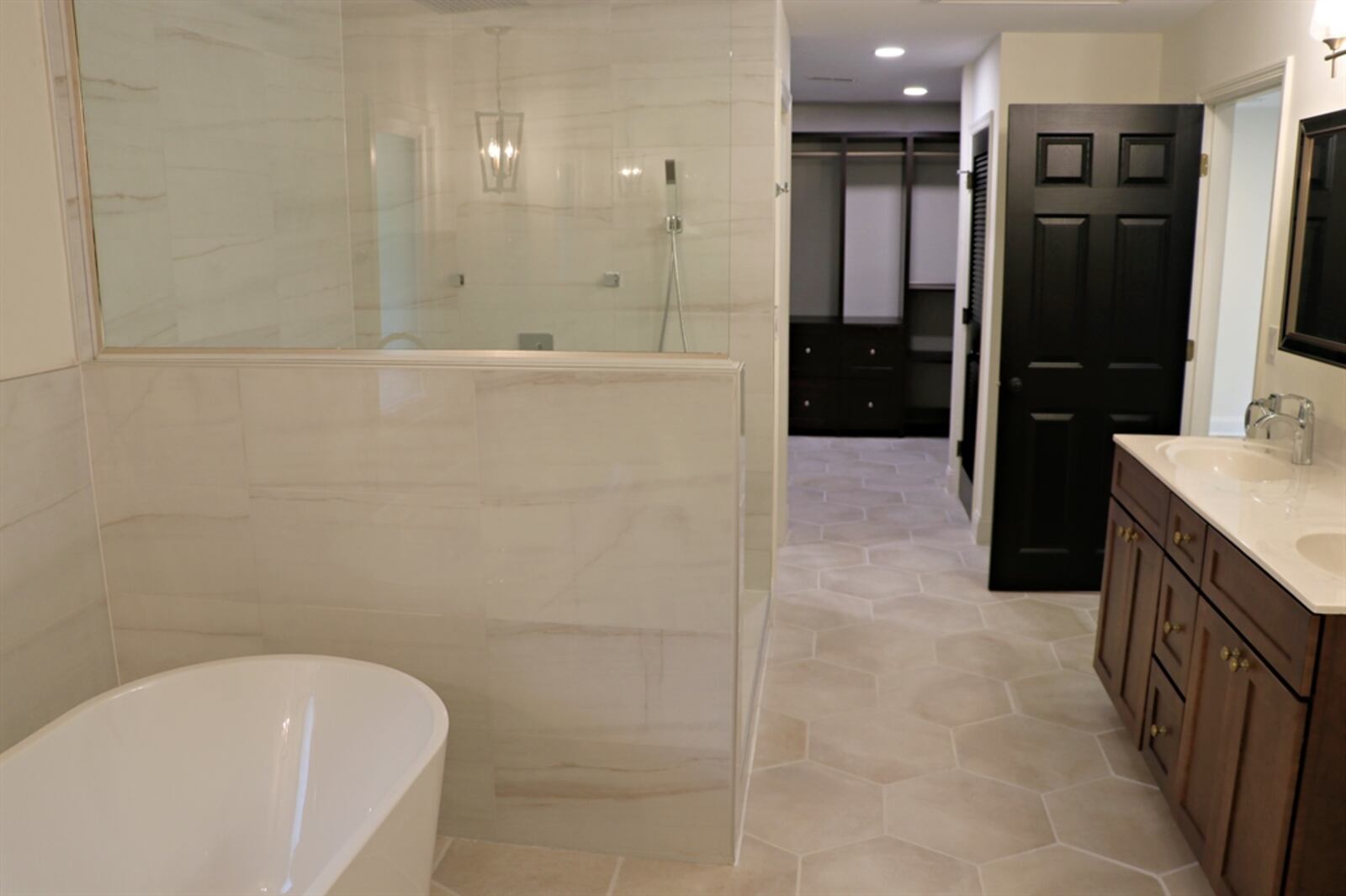 The primary bathroom has a walk-in shower with rain shower and jetted body sprays. The shower has marble-and-glass surround with a mosaic tile floor. 