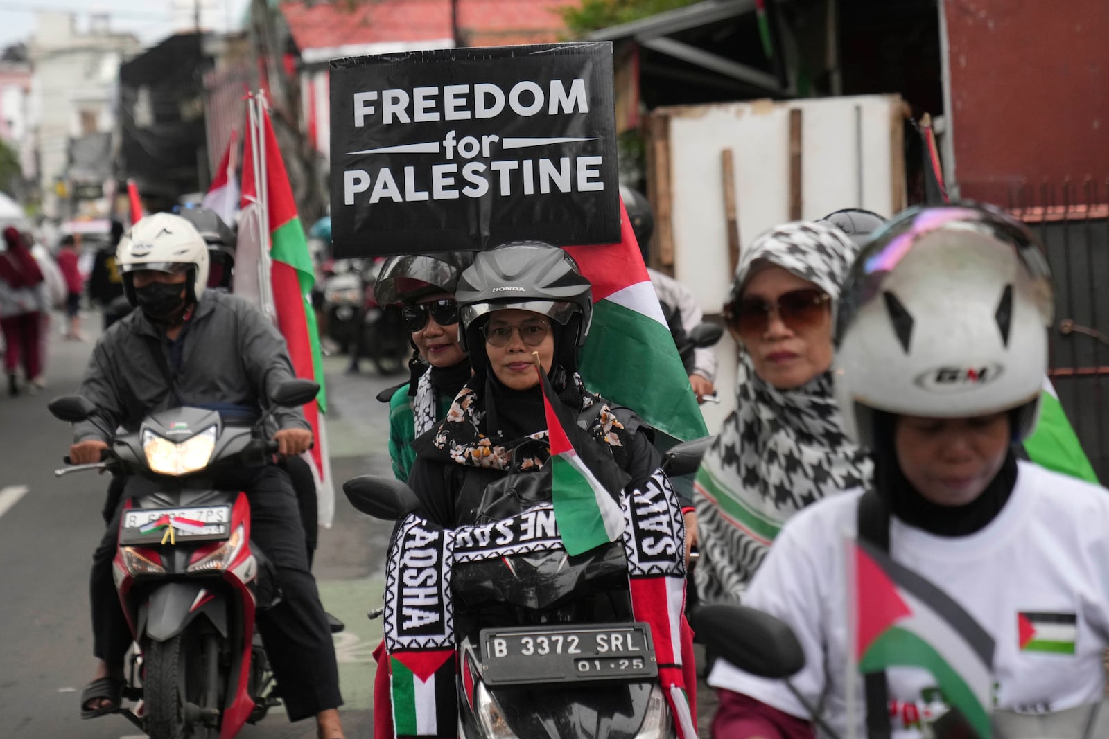 Muslim women display a poster as they ride motorcycles during a rally celebrating the announcement of the ceasefire deal between Hamas and Israel, in Jakarta, Indonesia, Saturday, Jan. 18, 2025. (AP Photo/Dita Alangkara)