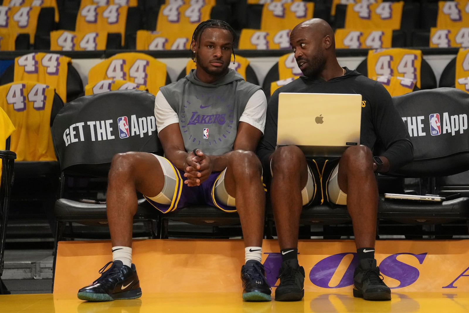 Los Angeles Lakers guard Bronny James, left, sits with a team member before an NBA basketball game against the Minnesota Timberwolves, Tuesday, Oct. 22, 2024, in Los Angeles. (AP Photo/Eric Thayer)