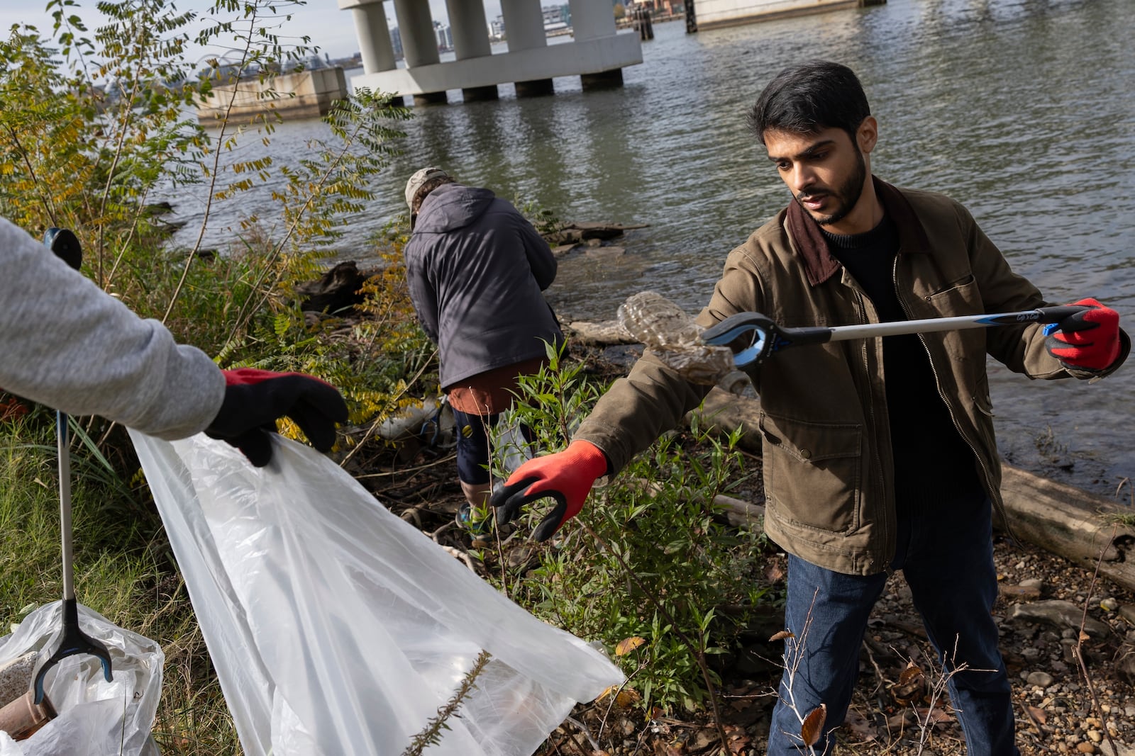 FILE - Volunteers collect trash items during a park cleanup on Nov. 15, 2023, at Anacostia Park in Washington. (AP Photo/Tom Brenner, File)