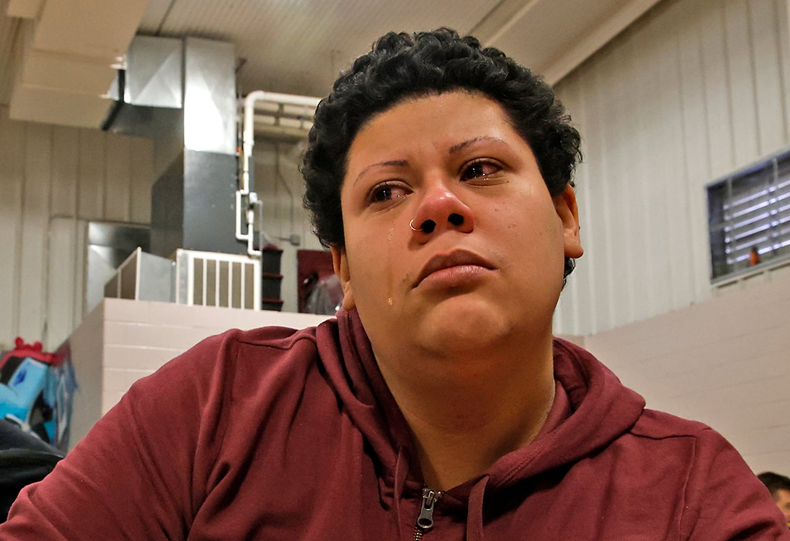 A tear runs down the cheek of Tsunami Lopez, 26, as she talks about being homeless in the bitter cold Tuesday, Jan. 16, 2024 in the Springfield Salvation Army gymnasium. The City of Springfield is partnering with the Nehemiah Foundation Faith Community Crisis Response Team, the Salvation Army, Sheltered Inc. and Homefull and has opened an Extreme Cold Weather Homeless Shelter to help those living on the street escape the bitter cold. BILL LACKEY/STAFF