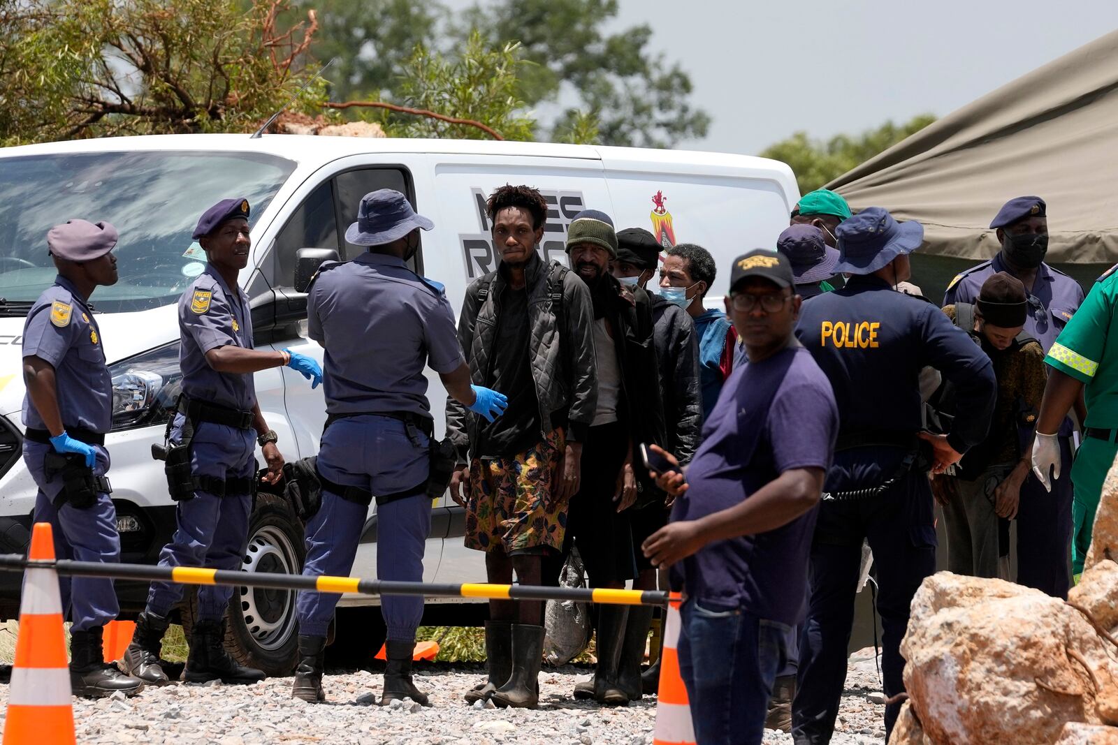 Miners are escorted by police officers after being rescued from below ground in an abandoned gold mine for months, in Stilfontein, South Africa, Tuesday, Jan. 14, 2025. (AP Photo/Themba Hadebe)