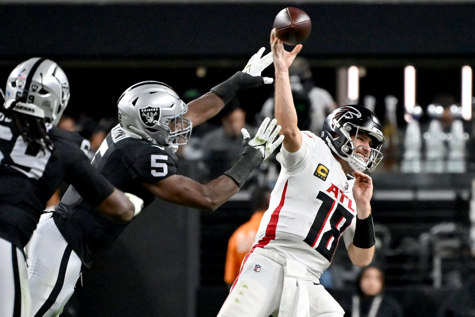 Atlanta Falcons quarterback Kirk Cousins (18) throws under pressure from Las Vegas Raiders linebacker Divine Deablo (5) during the first half of an NFL football game, Monday, Dec. 16, 2024, in Las Vegas. (AP Photo/David Becker)